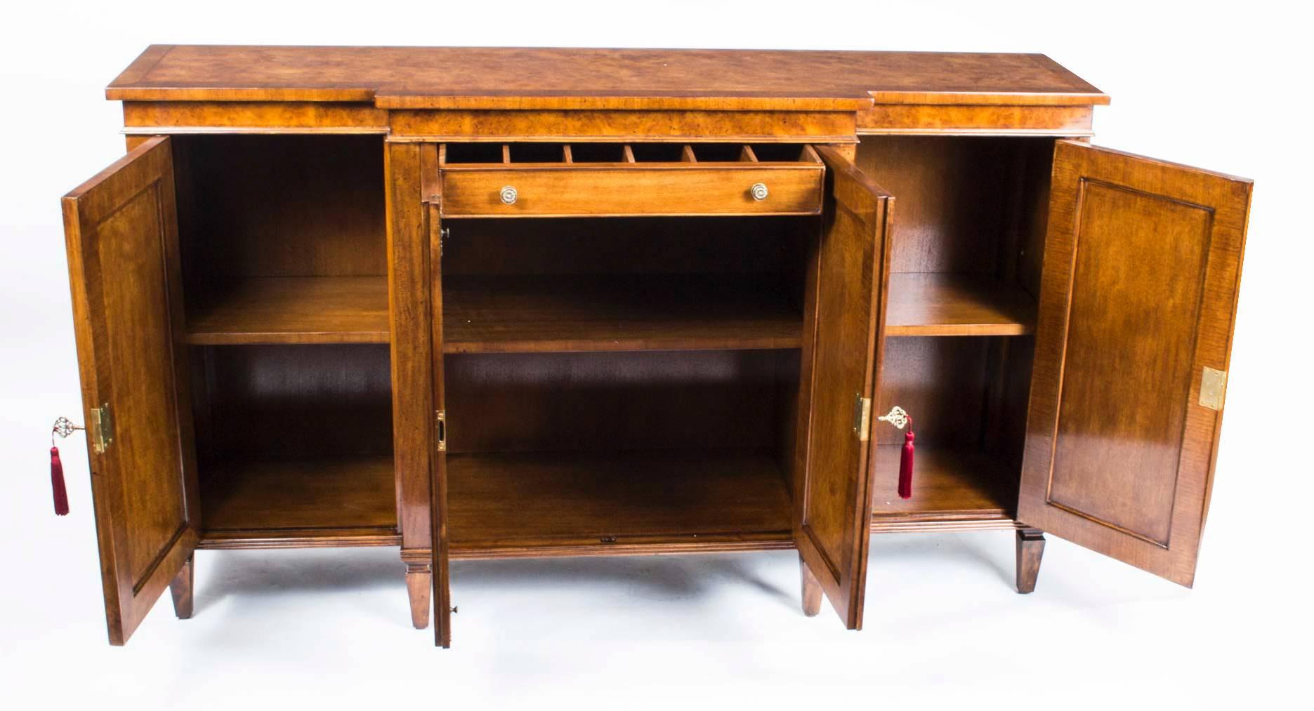 This is a wonderful breakfront burr walnut sideboard with room for all your plates, china, glassware and cutlery, dating from the last quarter of the 20th century.

It has four doors and that open to reveal a central drawer, for cutlery, etc. and