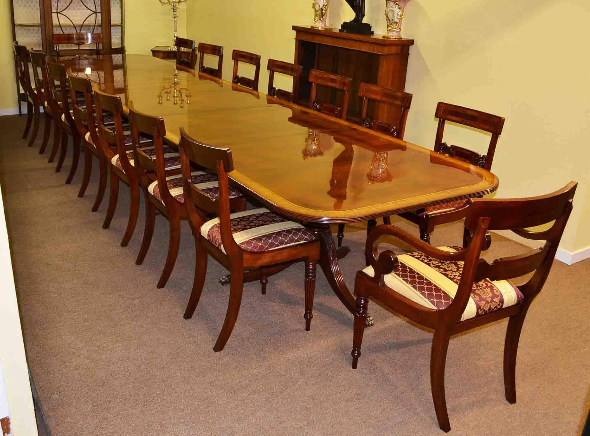 This is a beautiful Regency style dining table complete with the matching set of sixteen chairs, dating from the last quarter of the 20th century.

The table is made of flame mahogany with superb satinwood crossbanded decoration. It will seat
