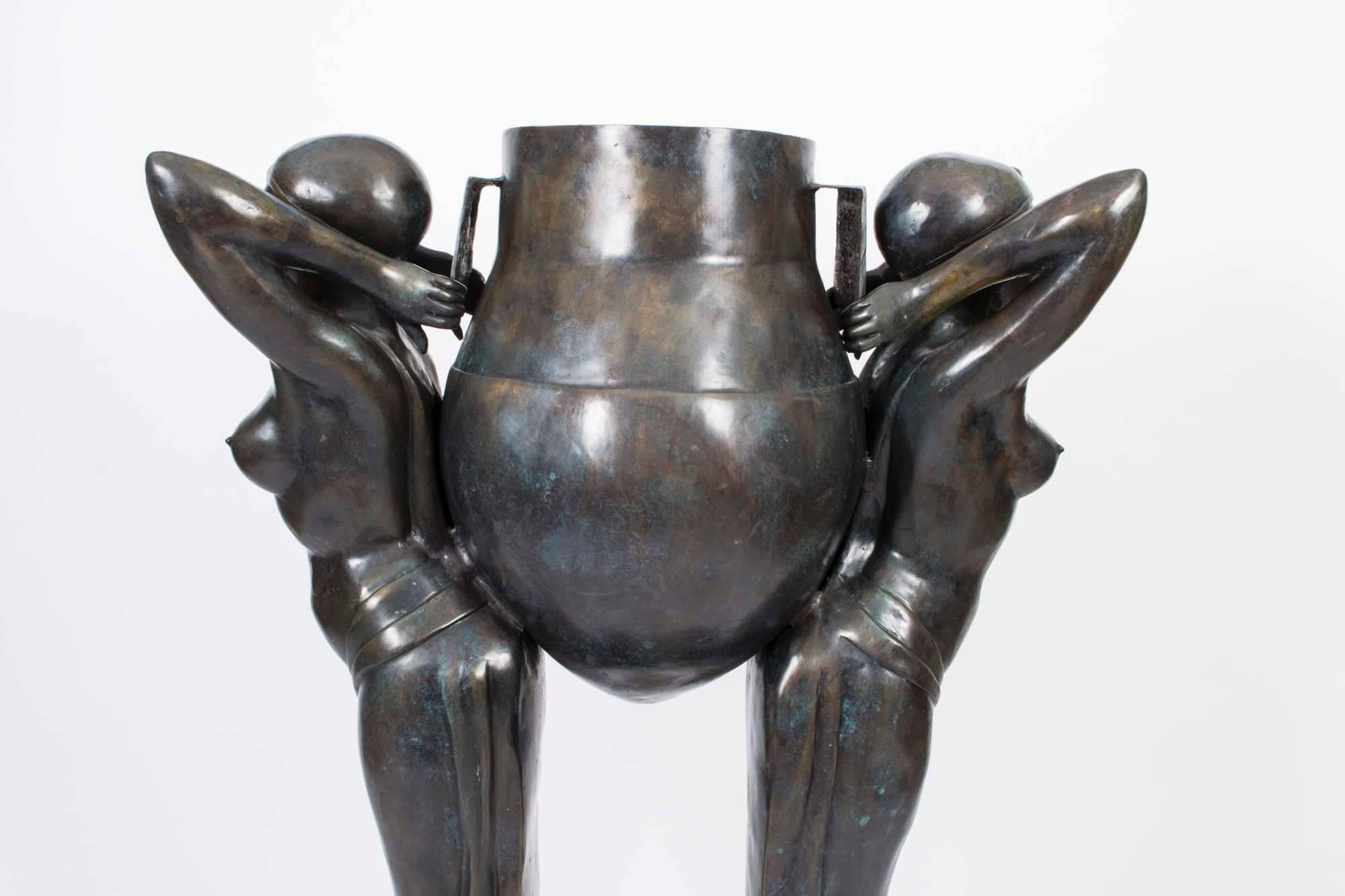 This is a truly stunning monumental life-size jardiniere depicting a pair of semi nude female figures wearing flowing skirts standing back to back holding an Etruscan urn.

In timeless Art Deco style, made in solid bronze using the lost wax