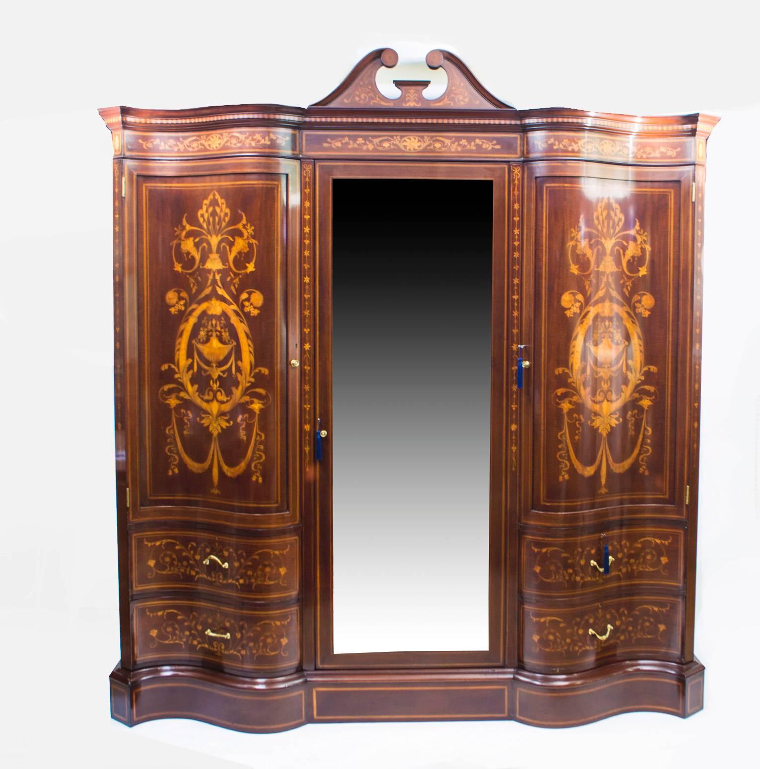 This is a spectacular antique late Victorian mahogany and floral marquetry bedroom suite comprising, a serpentine shaped wardrobe a dressing table and a washstand by the renowned cabinet maker and retailer Edwards & Roberts, circa 1880 in