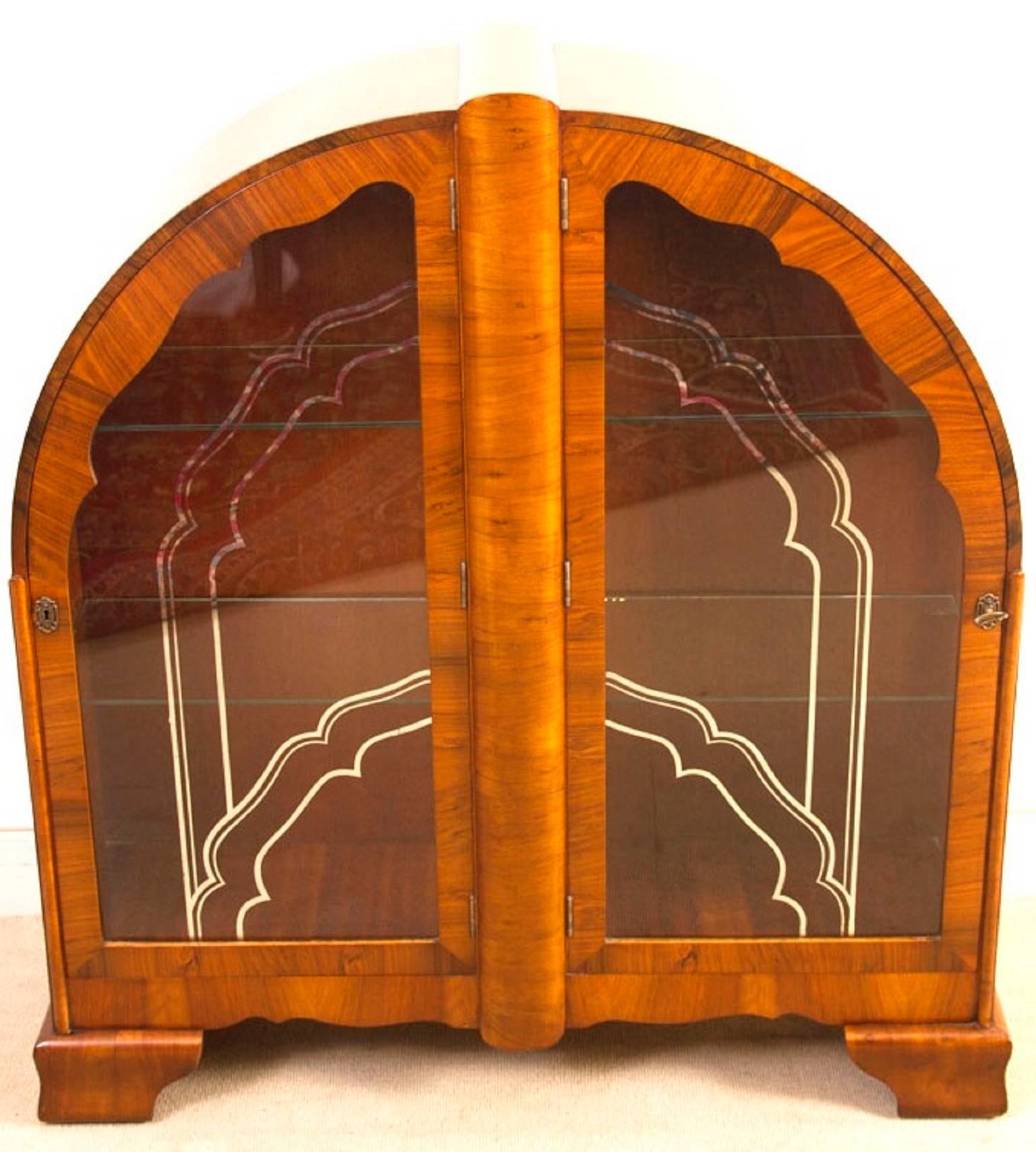 This is a lovely antique Art Deco burr walnut domed display cabinet, circa 1920.

The cabinet features inward hinged glass doors with the original silvered glazing and two glass shelves.

It stands on striking shaped bracket feet.

It is an