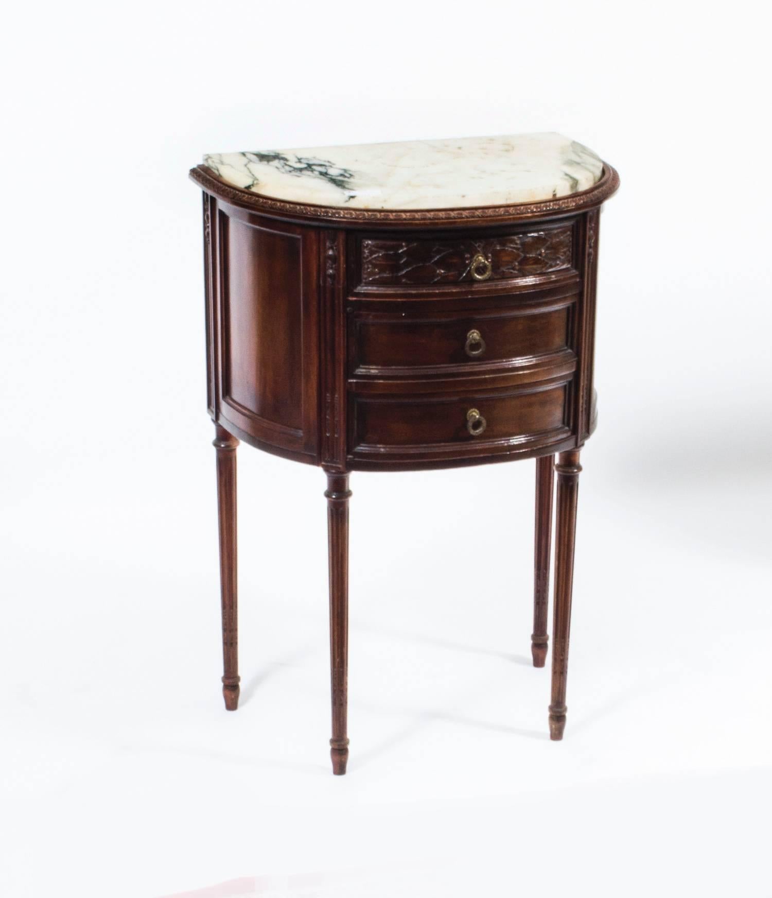 This is a thoroughly delightful and rare pair of antique Italian D-shaped marble topped bedside cabinets, circa 1900.

They have been accomplished in mahogany and each has a fantastic laurel carved drawer over two faux drawer fronts which are