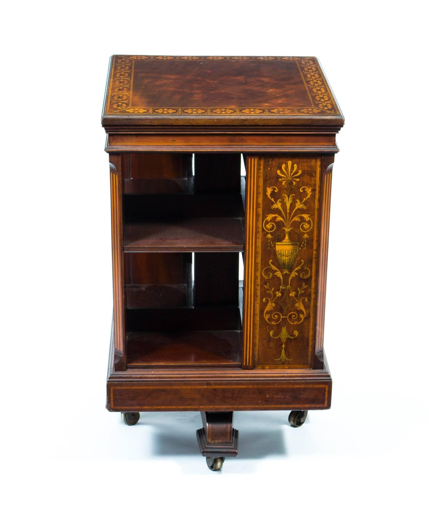 This is an exquisite antique Victorian revolving bookcase, circa 1890.

This lovely piece is attributed to the renowned retailer Maple & Co and is made of flame mahogany with an exquisite satinwood, boxwood and ebony marquetry and cross