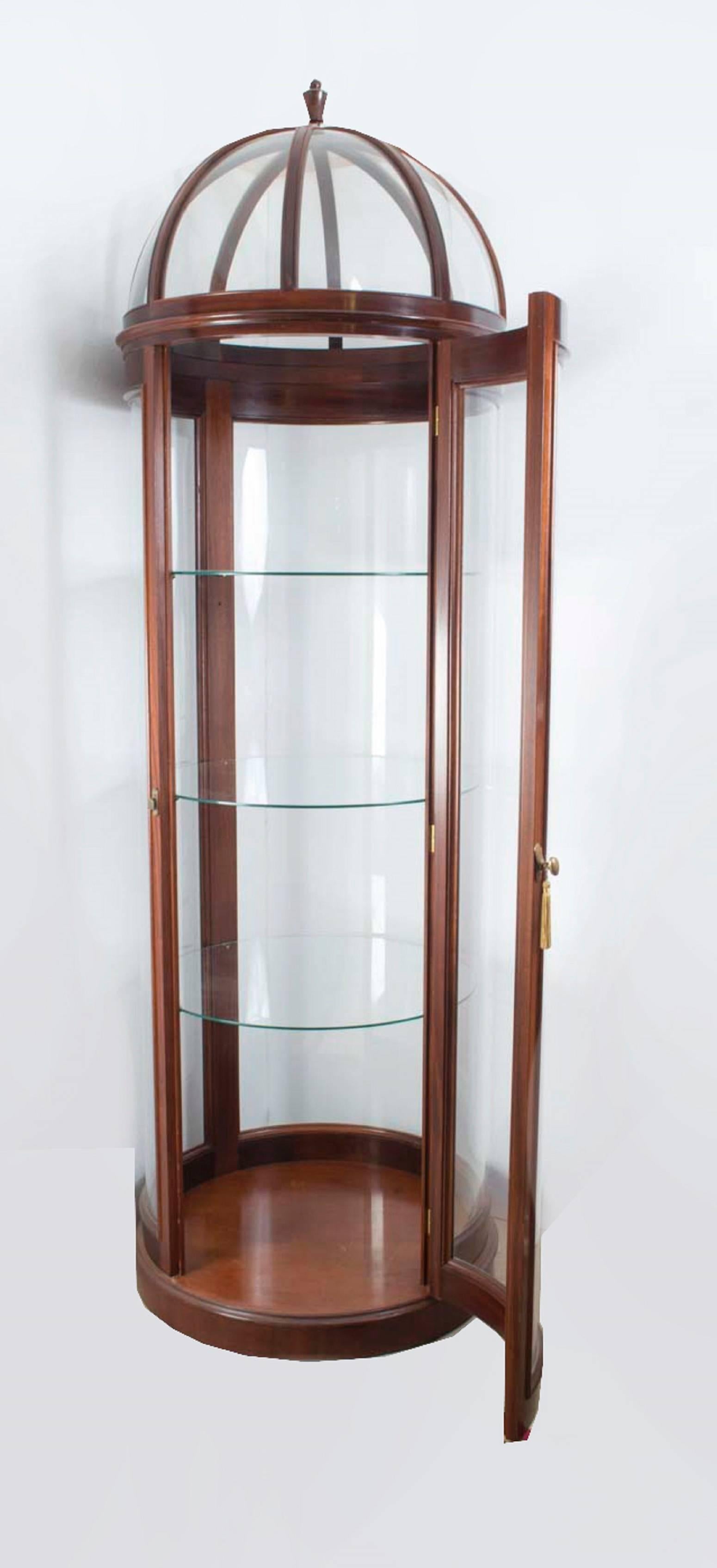 This is an exquisite and uniquely designed domed circular glass display cabinet, dating from the last quarter of the 20th century.

This tall display cabinet has been accomplished in an elegant mahogany and glass. Each side of the cabinet consists