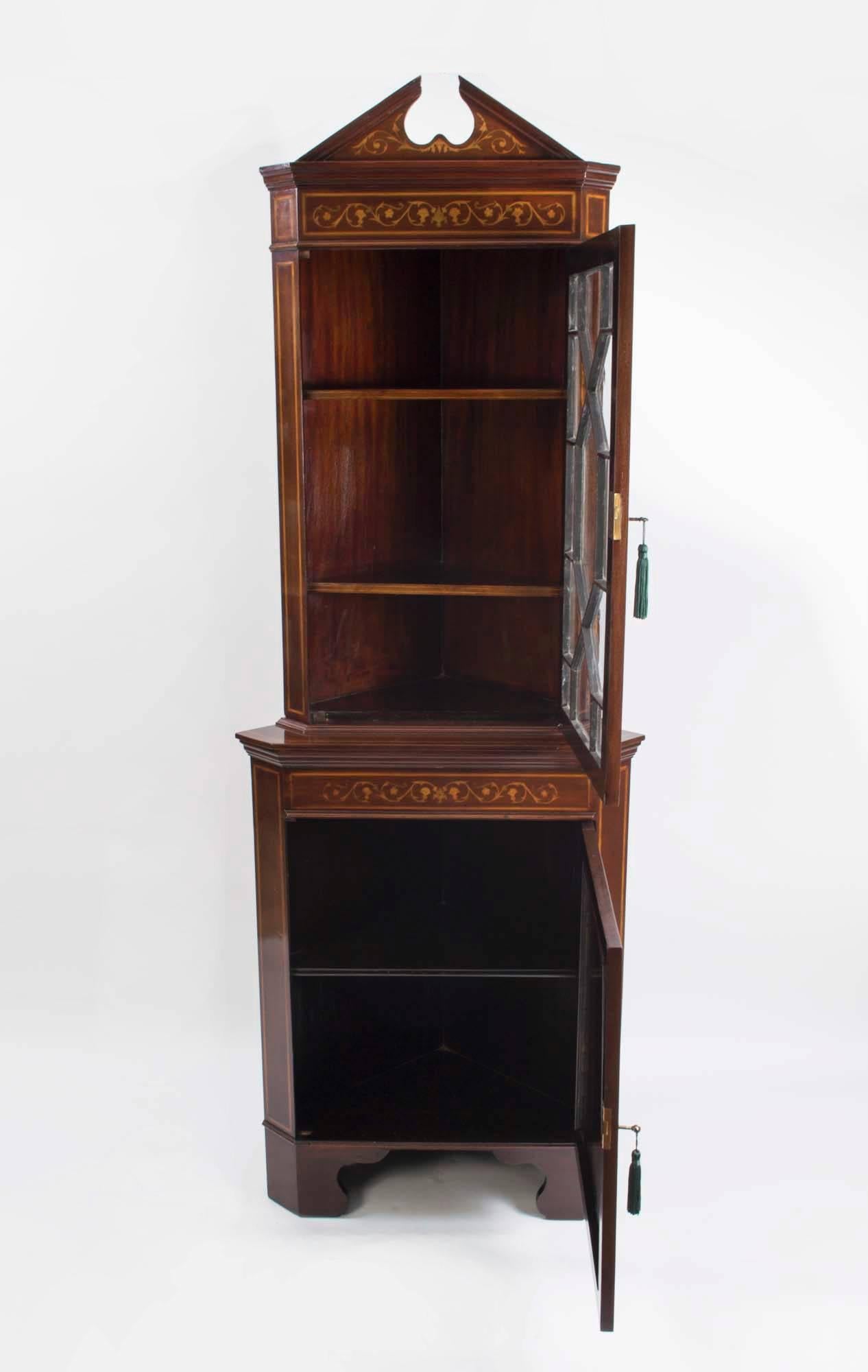 This is a fabulous antique English Edwardian profusely inlaid corner cabinet, circa 1880 in date.

The cabinet is made of rich mahogany and has satinwood inlay with garlands, swags, urns and floral motifs, as well as satinwood and ebony