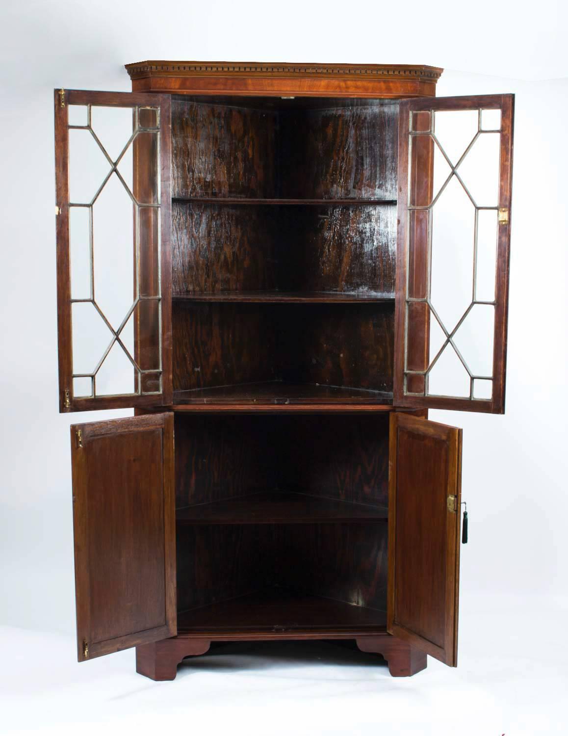 This is a fabulous antique English Edwardian, mahogany two door corner cabinet profusely inlaid with satinwood and ebony crossbanding with boxwood and ebony stringing.

It dates from circa 1890, the end of the Victorian period and the start of the