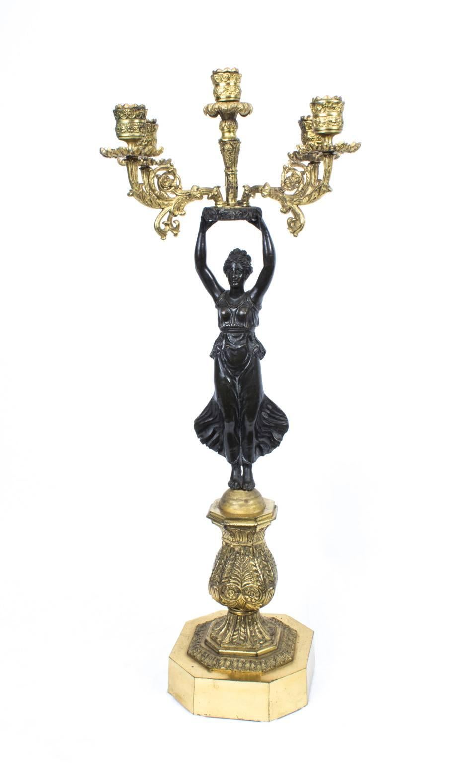 This is an extraordinary large antique pair of dark patinated bronze and gilded ormolu five-light, four branch Empire candelabra, circa 1860 in date.

Each is cast as a classical muse and stands on canted square plinths cast with acanthus.

There is