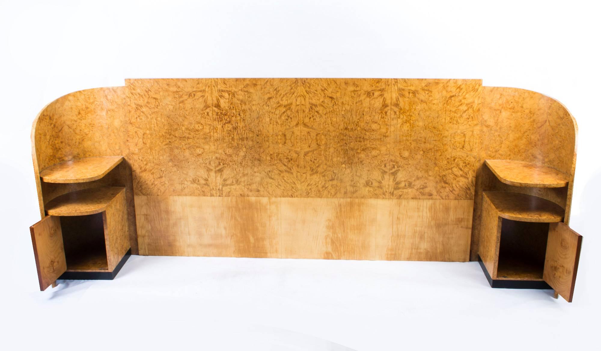 This is a super antique Art Deco bird's-eye maple headboard with downswept incurving ends incorporating a pair of bedside cabinets, each with two rounded shelves over a cupboard door. The cabinets have ebonized handles and are raised on elegant