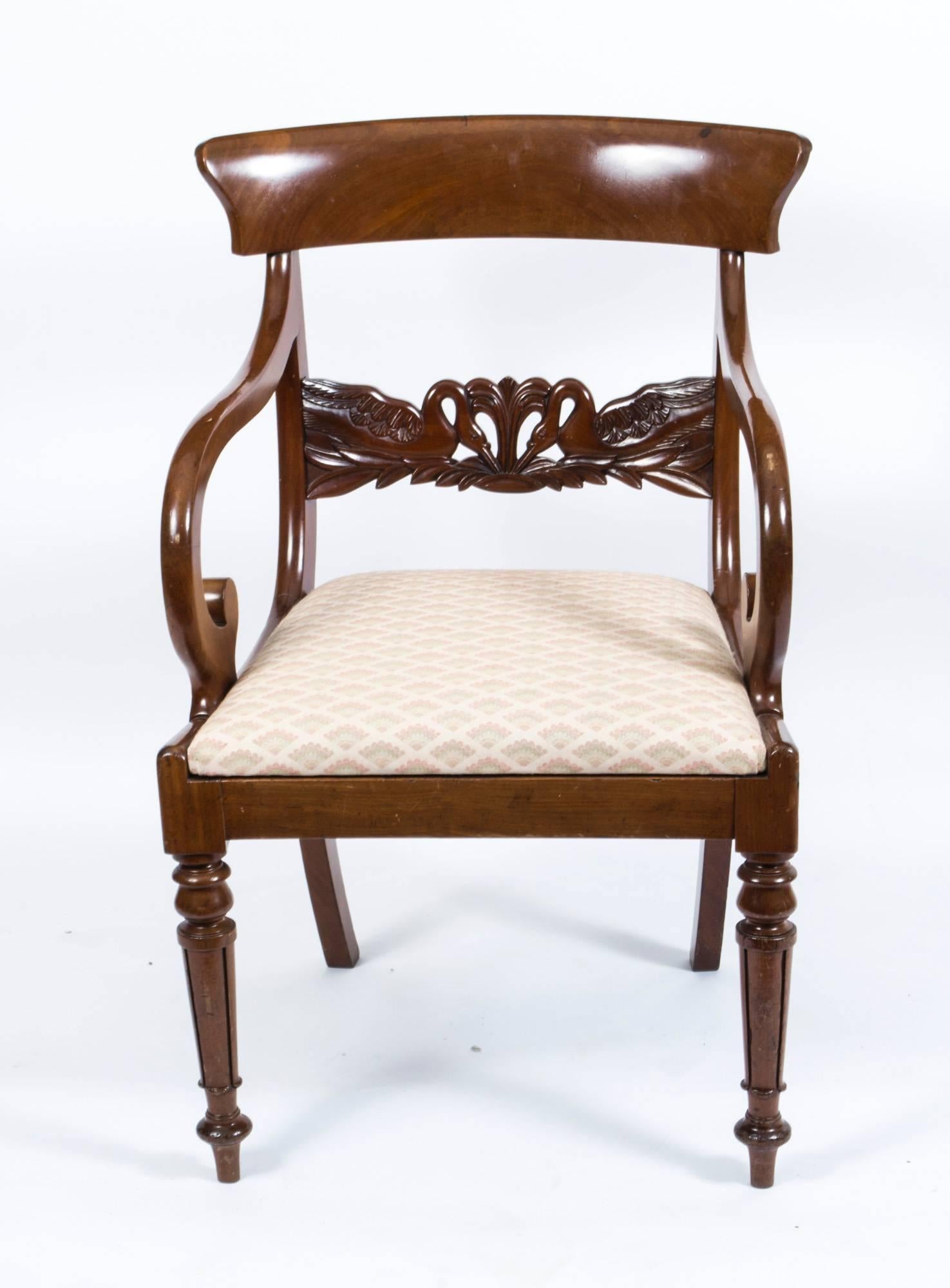 This is an elegant antique Regency mahogany elbow chair, circa 1820 in date.

The pair of downswept arms have scroll terminals and the horizontal rail is beautifully carved with a mirrored pair of swans.

The drop in seat is upholstered in a