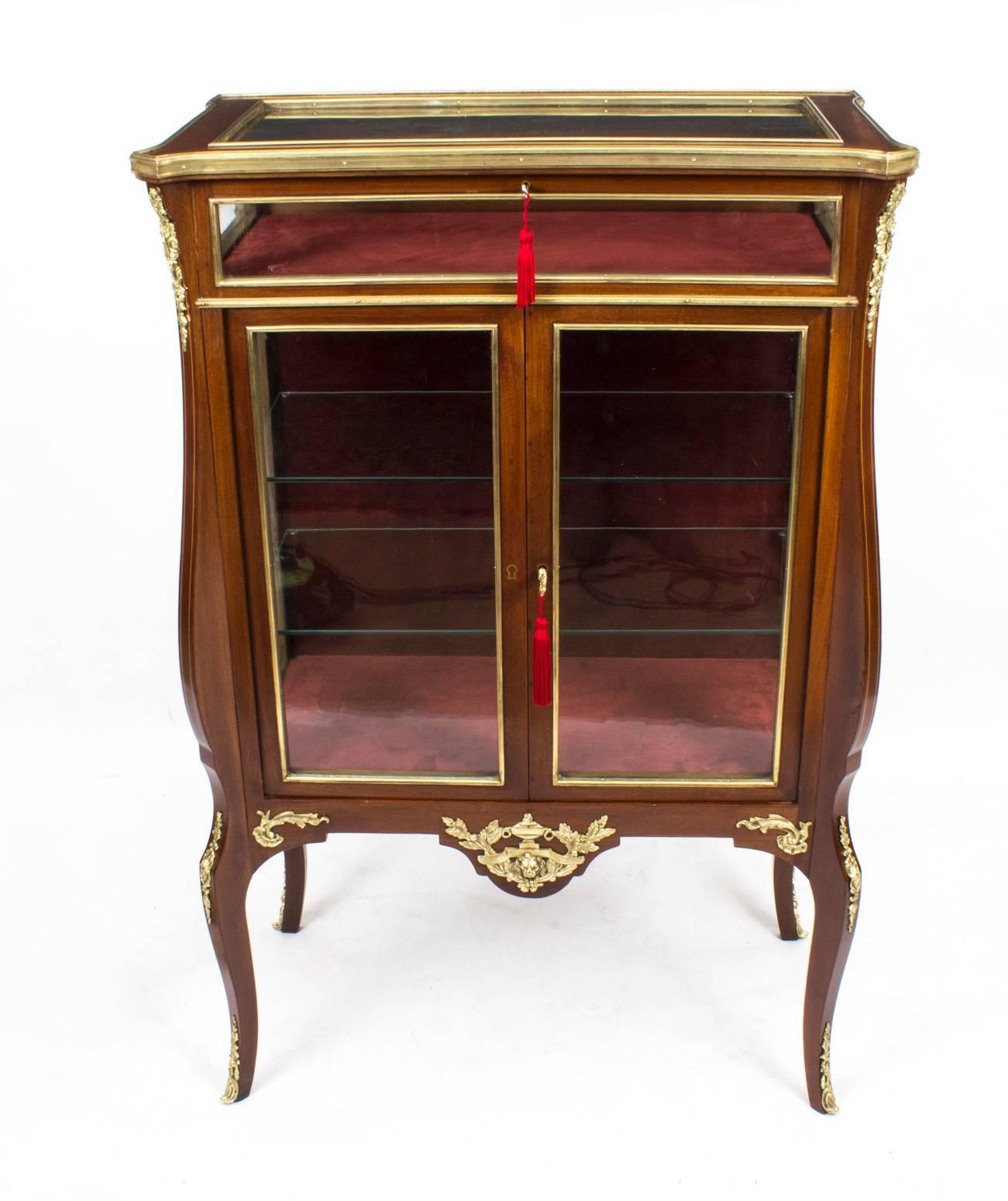 This is an exquisite antique French walnut bijouterie display cabinet, circa 1880 in date.

It has a useful glazed lidded bijouterie display case above a pair of glazed doors enclosing glass shelves, the whole decorated with exquisite ormolu