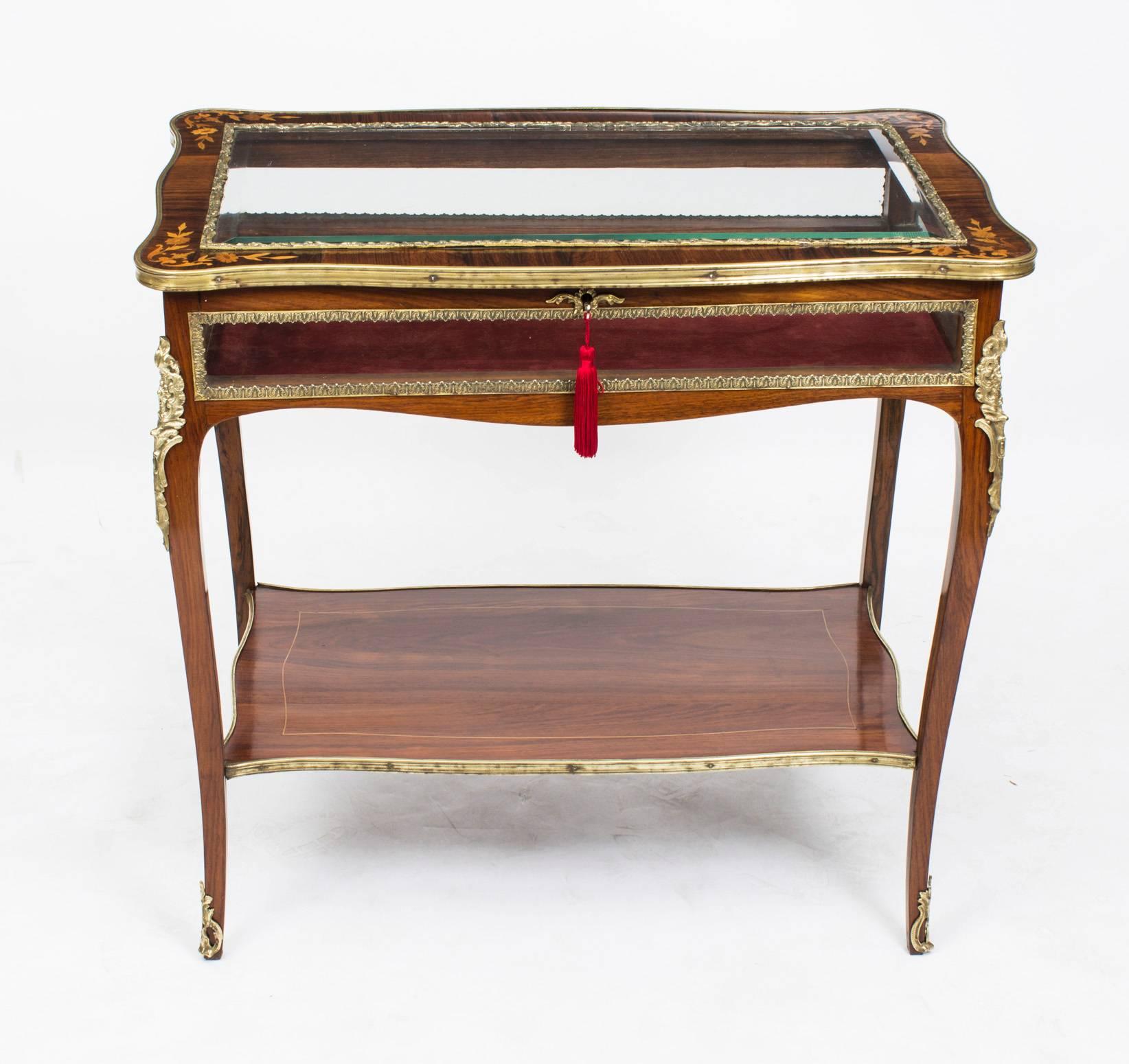 This is a beautiful antique French ormolu-mounted Rosewood and marquetry serpentine bijouterie table in the Louis XV manner, circa 1880 in date.

The hinged top with a bevelled glass pane, inlaid with a border of flowers and scrolling foliage. The