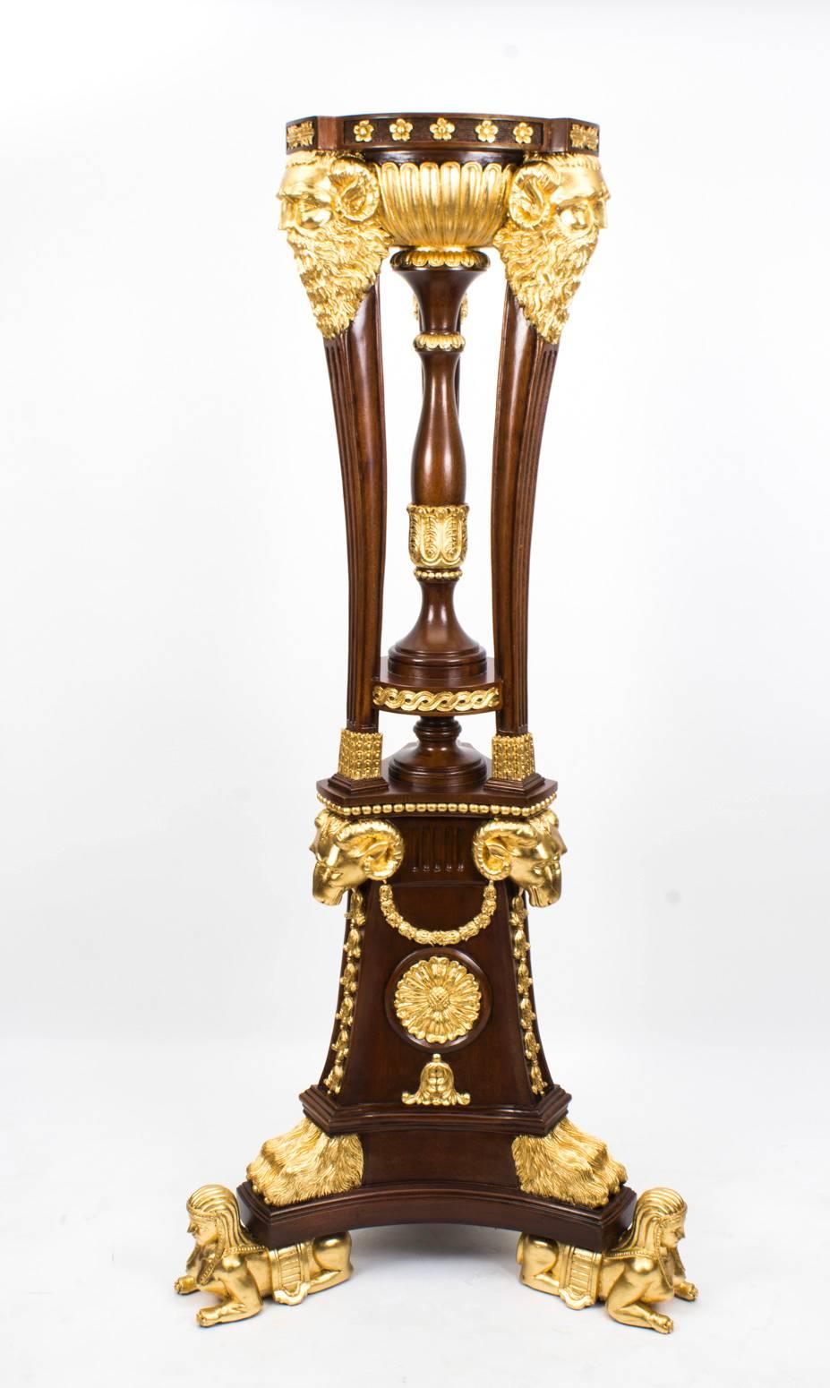 This extraordinary monumental pair of mahogany and giltwood torcheres of impressive size are in the ornate Empire style and date from the last quarter of the 20th century. 

The torcheres are supported by tall tripod bases on sphinx feet worked