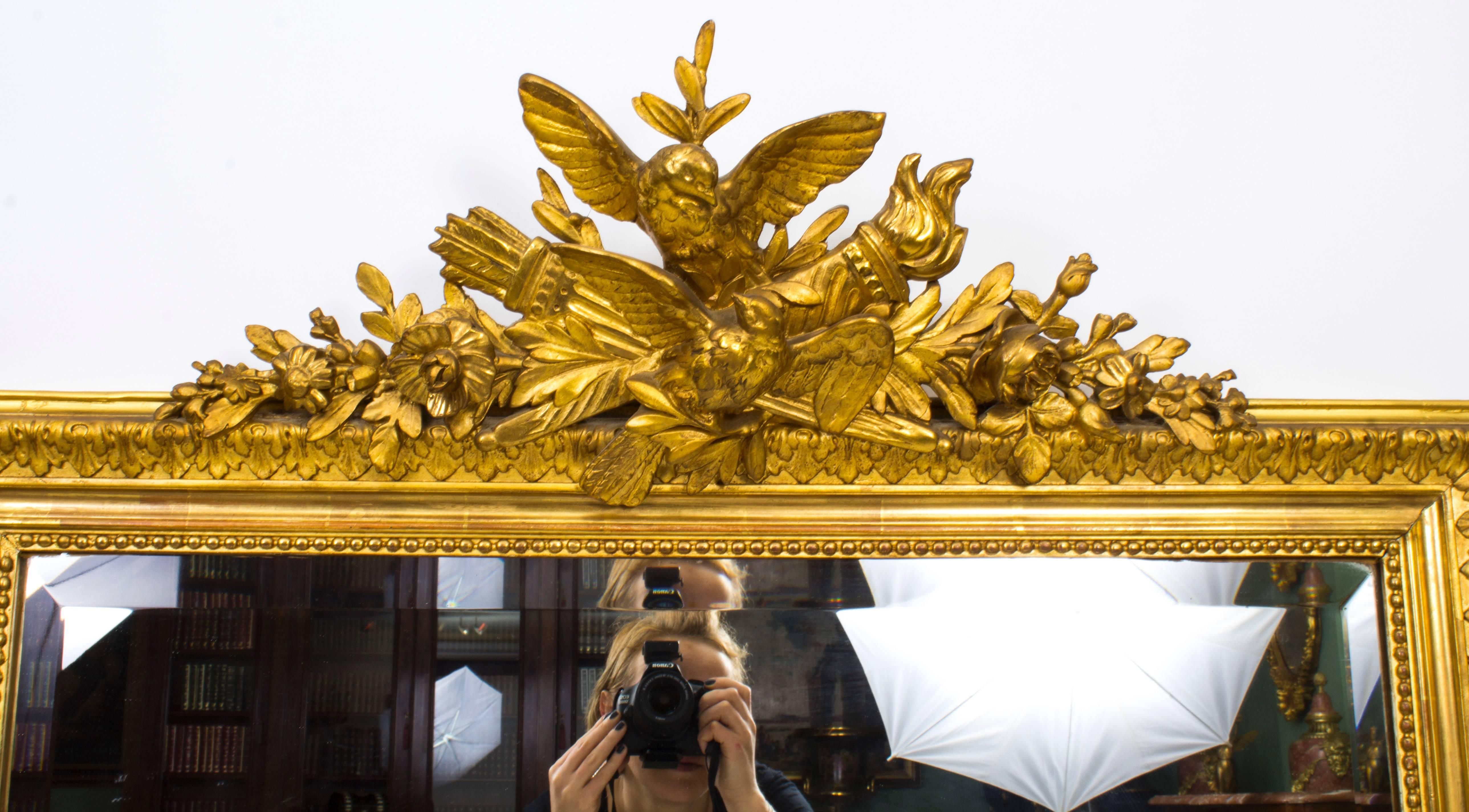 This is a beautiful large antique French carved giltwood overmantel mirror, circa 1860 in date.
The frame is surmounted with a striking carved giltwood central finial with doves, a flaming torch, a quiver of arrows and foliate and floral