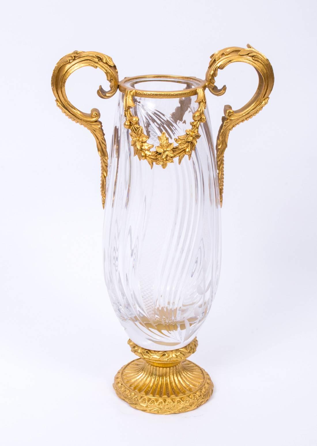 A remarkable pair of French ormolu-mounted and cut crystal vases dating from the last quarter of the 20th century.

These magnificent vases feature cut glass leaf contour scrolls and faceted diamond patterned details. The ormolu-mounted handles