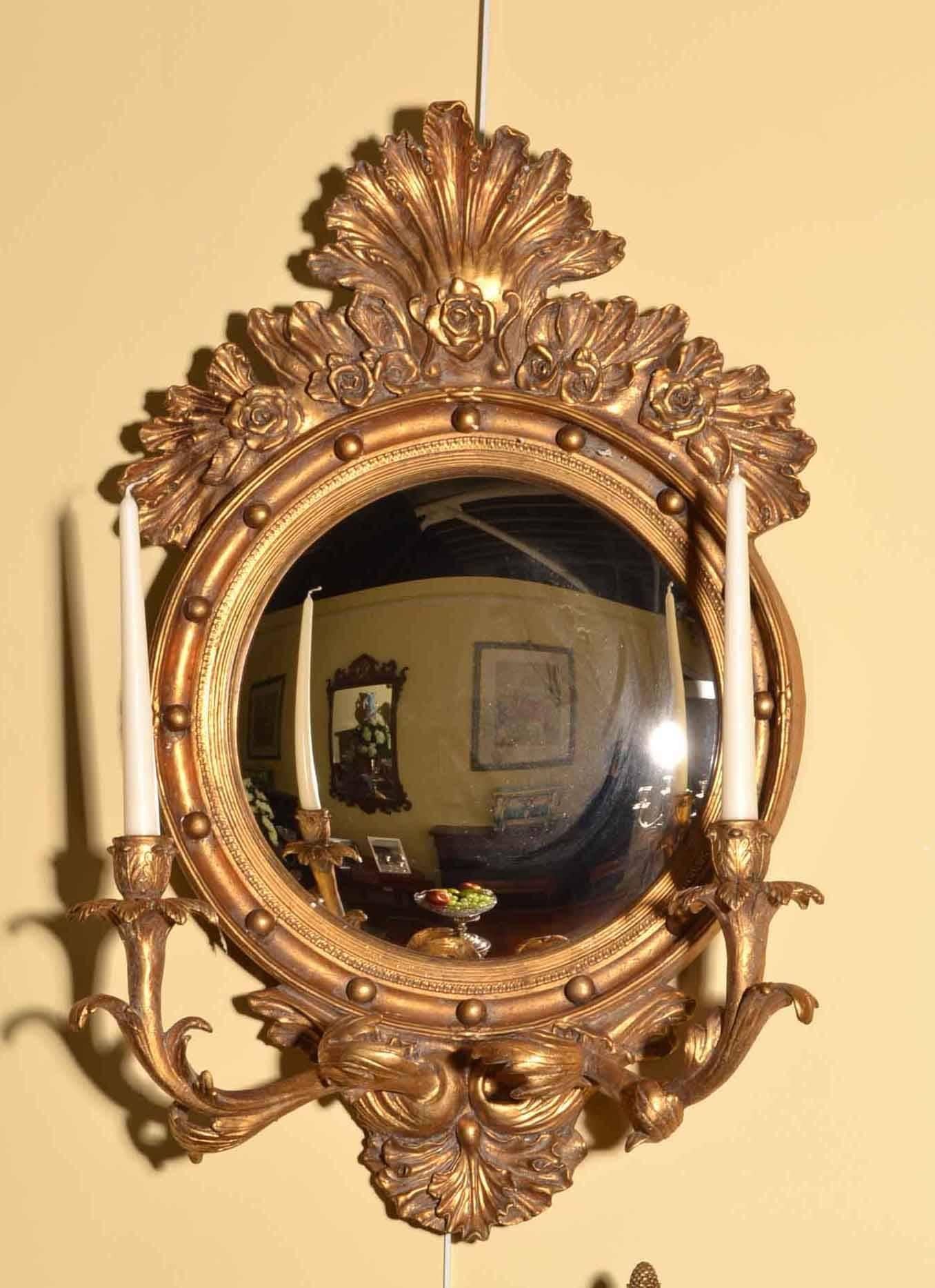 This is a beautiful and highly decorative pair of Italian gilt mirrors each with two candleholders, dating from the last quarter of the 20th century. 

They have convex mirrors and a beautiful antiqued finish.

The quality and craftsmanship is
