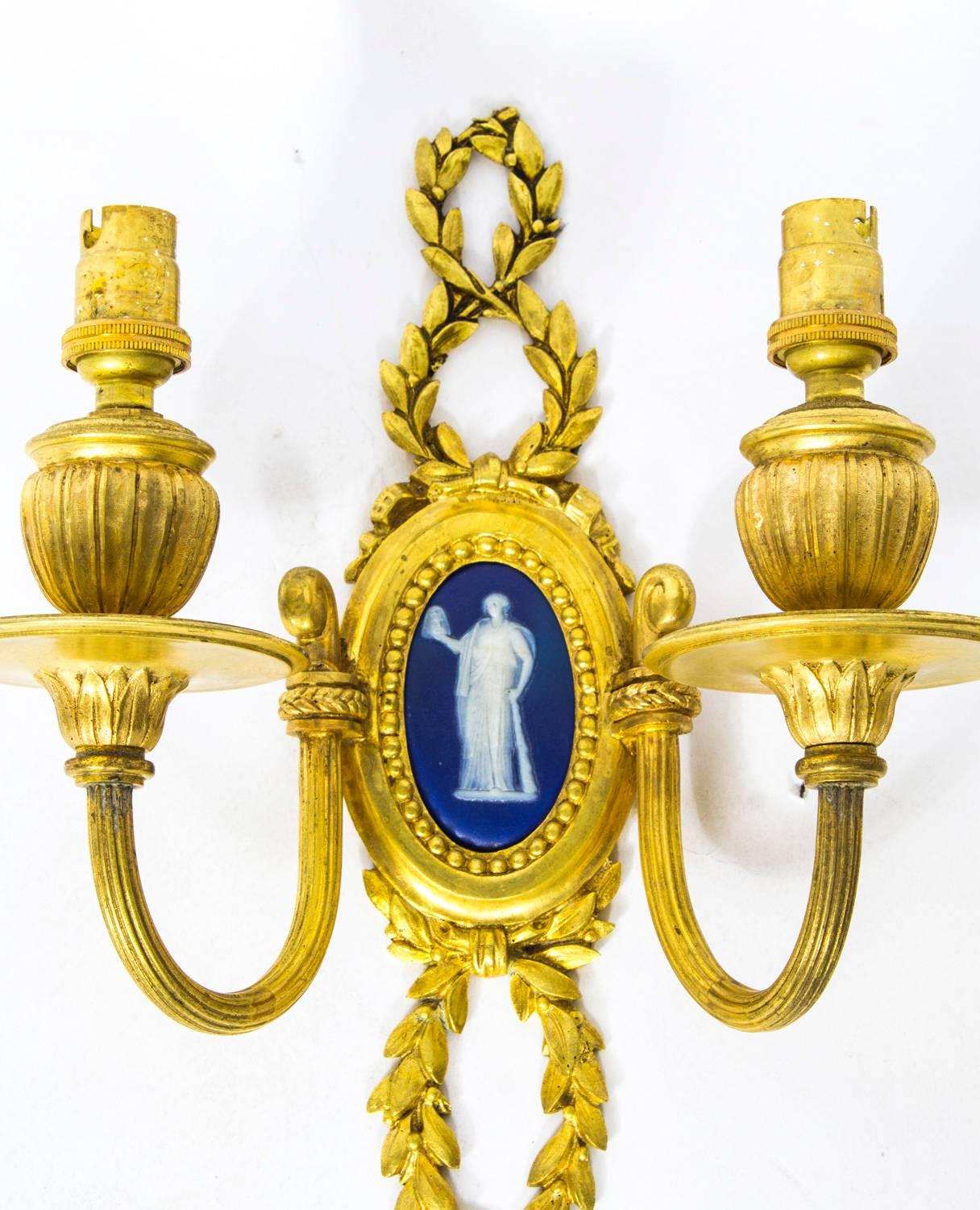 This is a stunning Antique pair of ormolu and Jasperware two branch wall lights, circa 1900 in date.

Of elegant classical form with upturned rope twist arms and foliate cast sconces. Each back plate is inset with a blue and white Jasperware