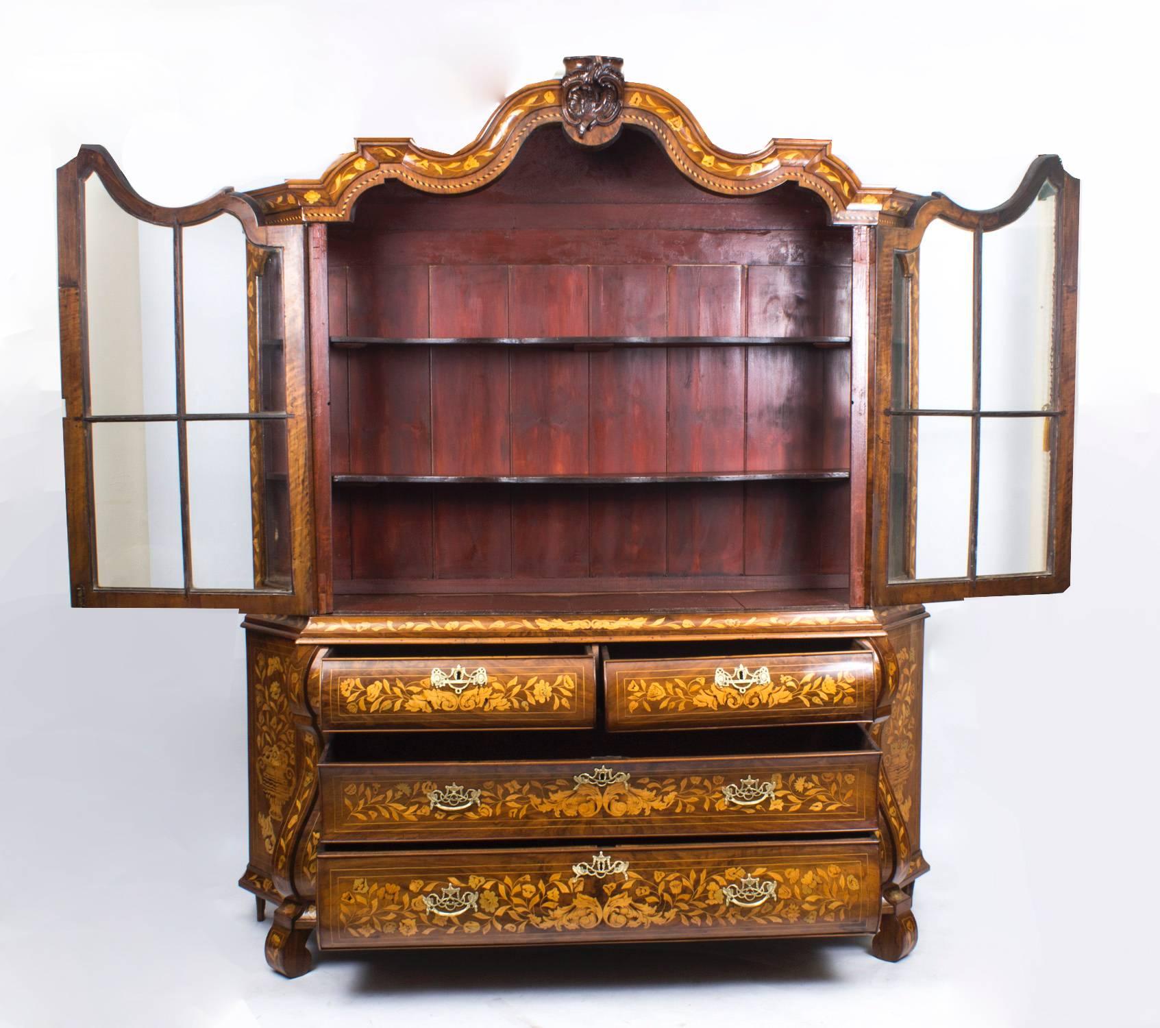 This is a stunning antique Dutch marquetry walnut bombe display cabinet, circa 1780 in date. 

It features the most wonderful hand cut floral marquetry, the central pair of glazed upper doors open to reveal two full width shelves, the canted