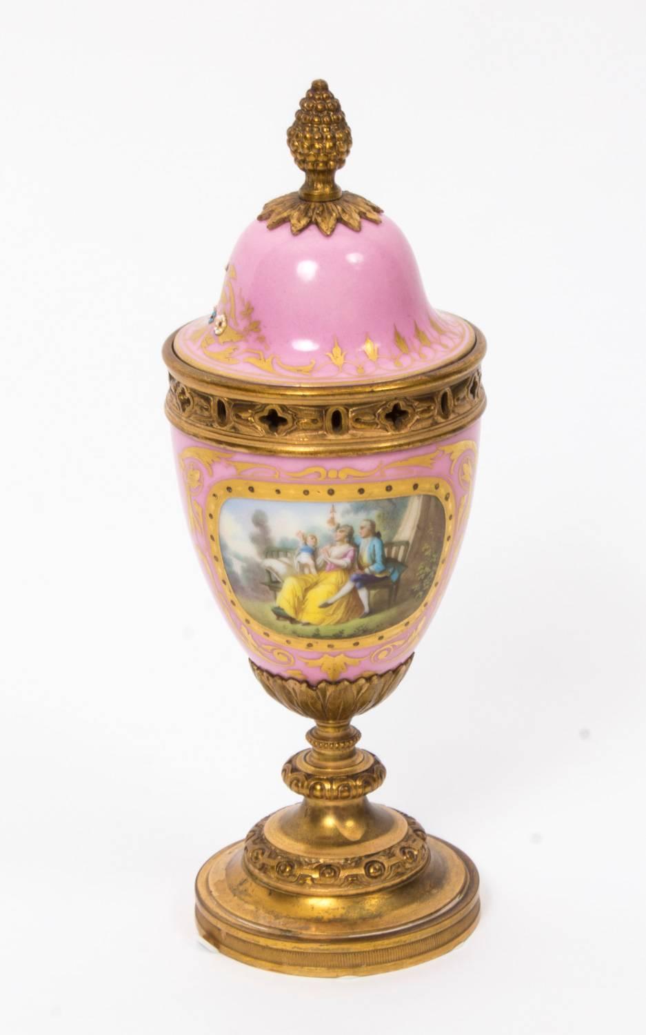 This is a stunning pair of French  Sevres " Rose Pink" hand painted porcelain and ormolu garniture urns, circa 1880 in date.

The porcelain bodies are hand painted with gilt framed cartouches depicting family groups, on one side and