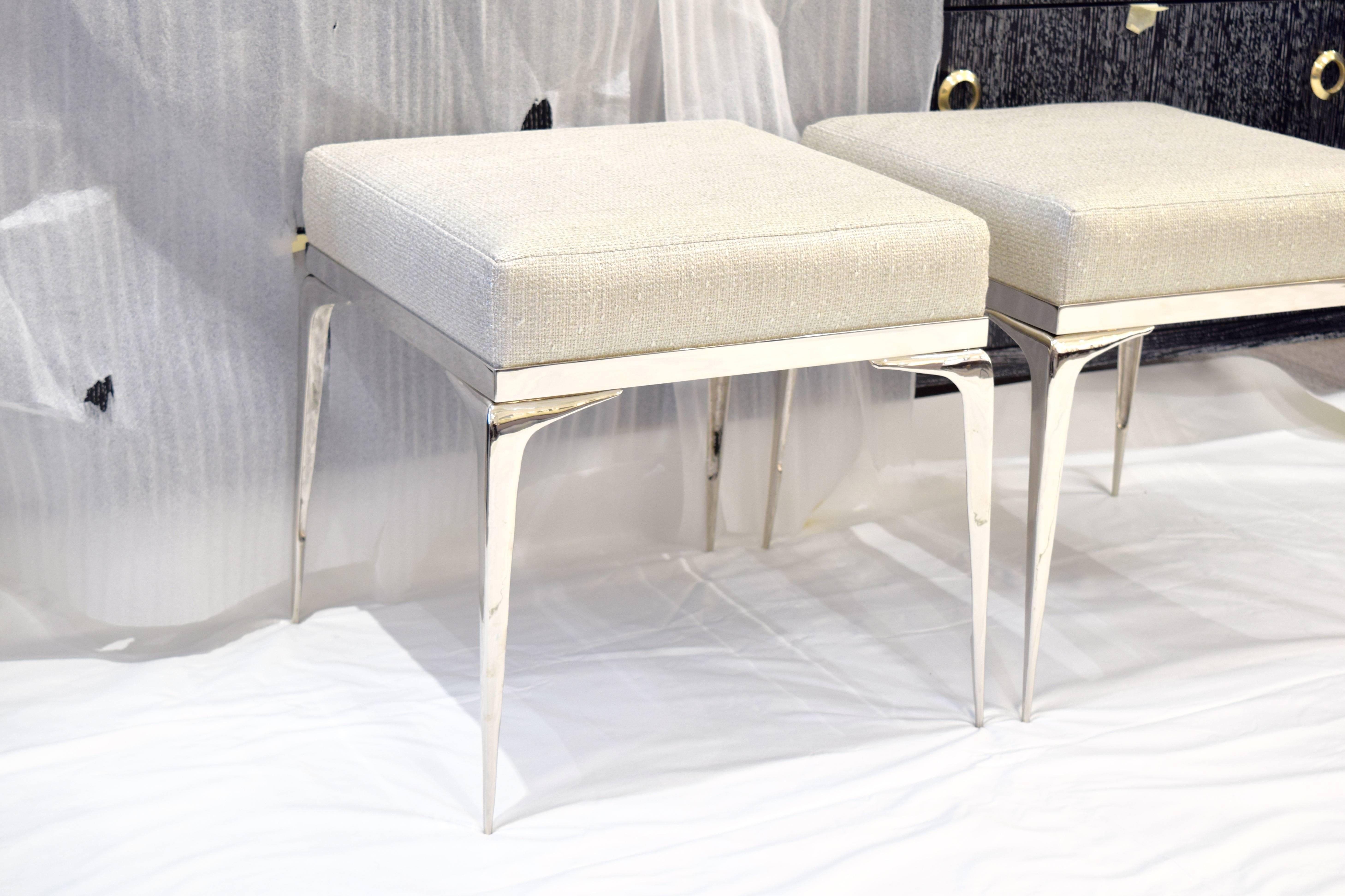Elegant pair of square signature Stiletto Ottomans designed by Irwin Feld Design for CF Modern.
An upholstered cushion is set in a polished nickel frame which attaches to four hand cast and hand polished nickel sculptural 