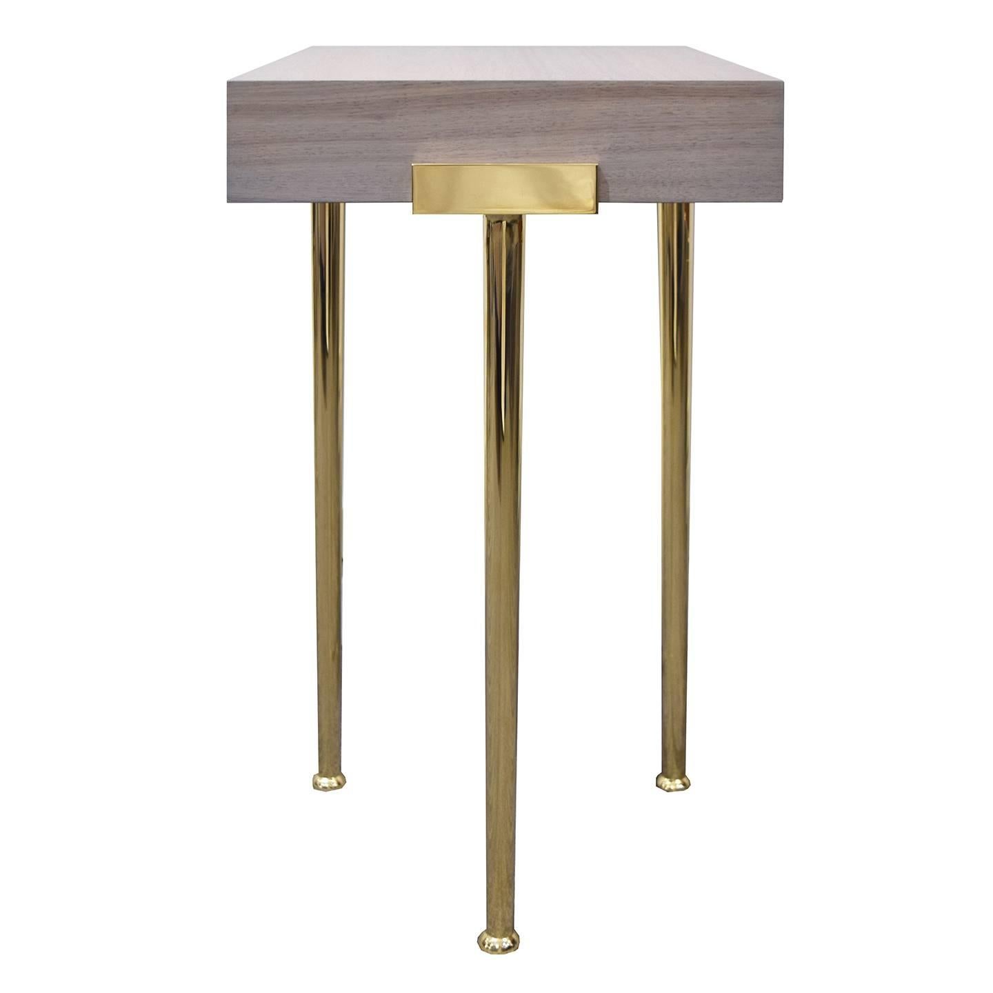 The Madison end table, designed by Irwin Feld Design for CF Modern, is a sophisticated stand for any living space. The table itself is made from a block of bleached walnut and stands on four stylish Madison legs, equipped with polished brass lips