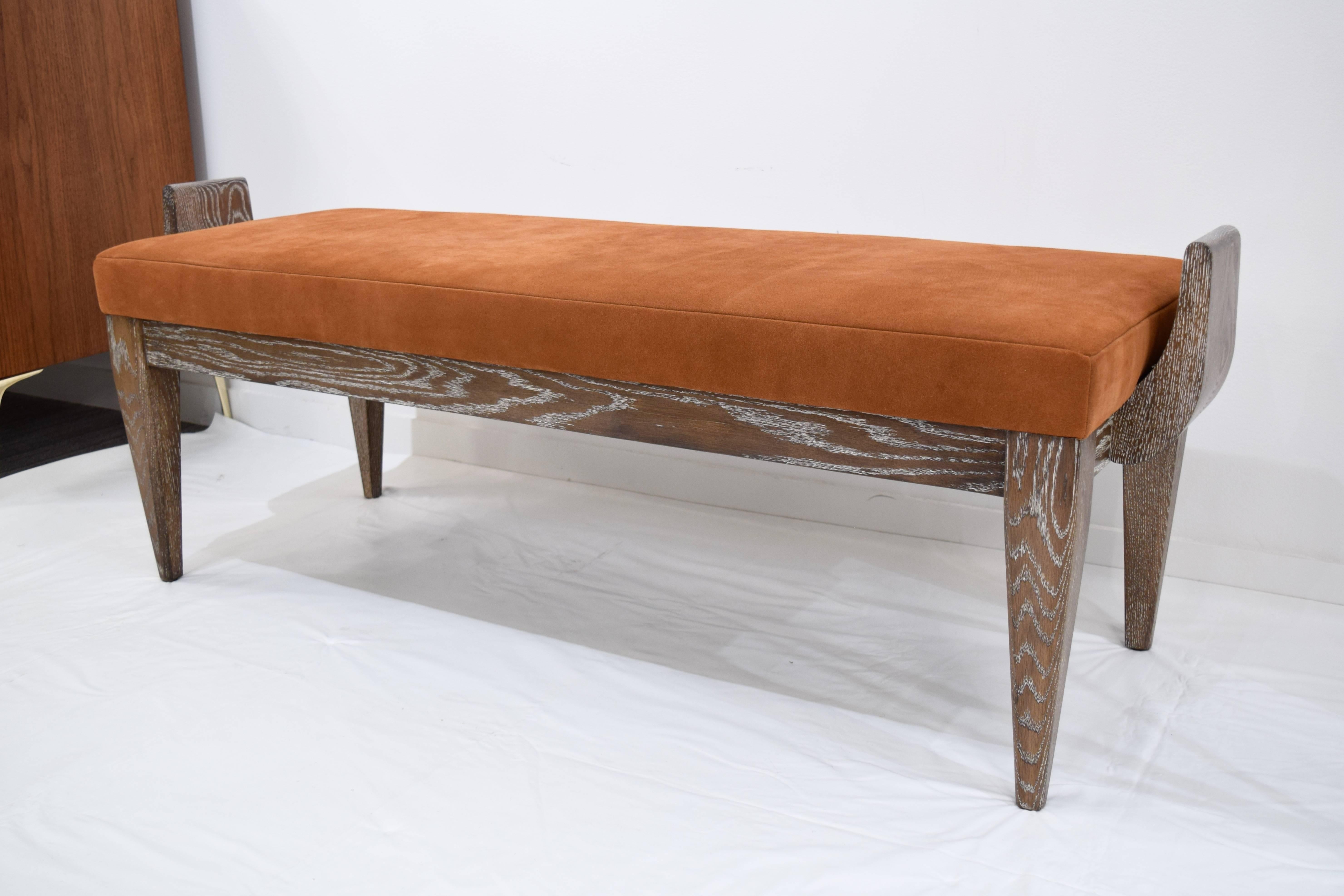 The ornate Atlas bench designed by Irwin Feld Design for CF Modern. An upholstered cushion in a burnt bronze suede is set atop a light brown cerused armed base. The piece is fully customizable and we do offer sample matching services. Lead time is