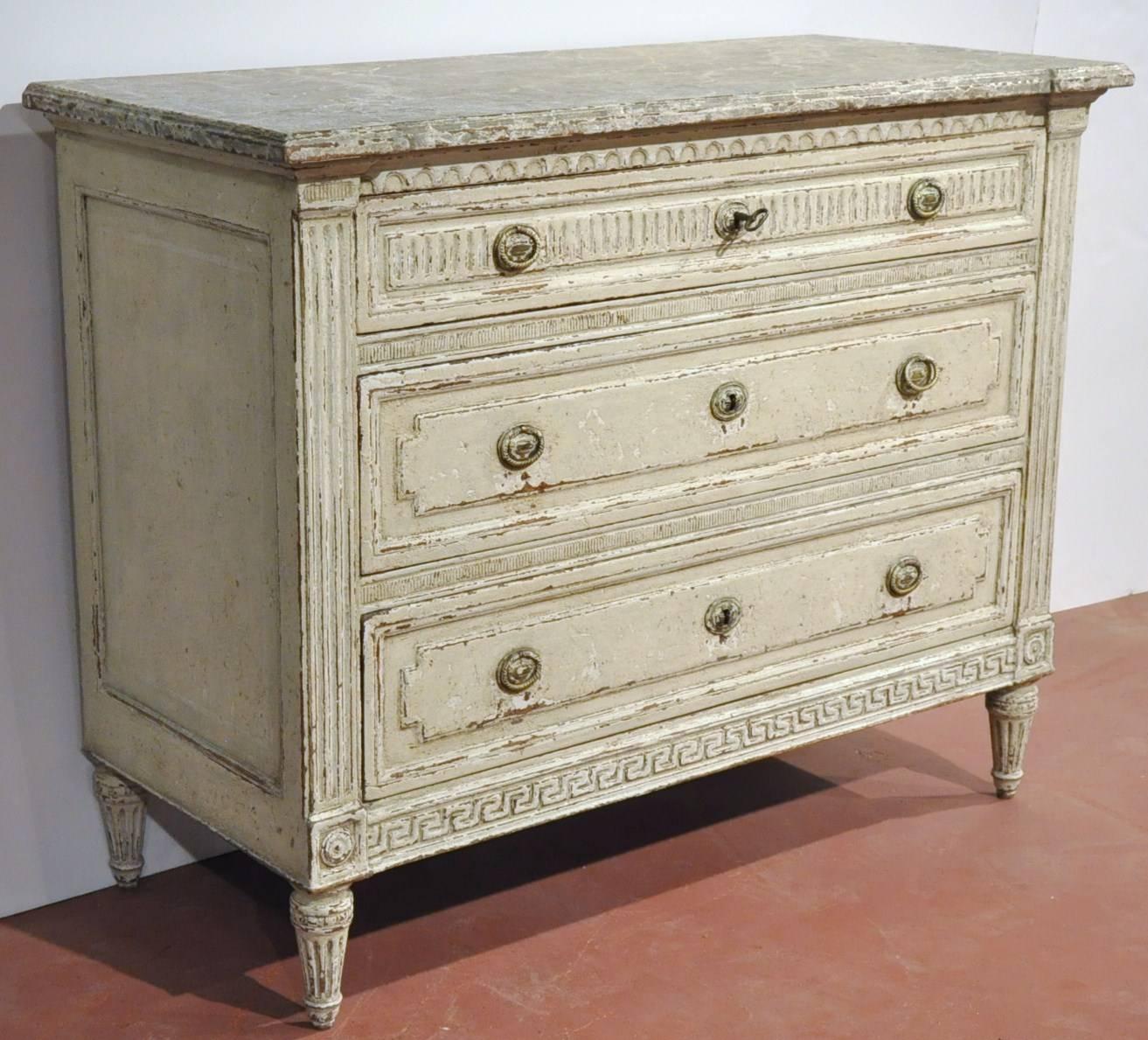Elegant pair of antique chests of drawers from France, circa 1860; each commode features detailed carved decor on the three drawers across the front including the posts on the sides, and hand carved corner medallions, Greek key design on the apron,