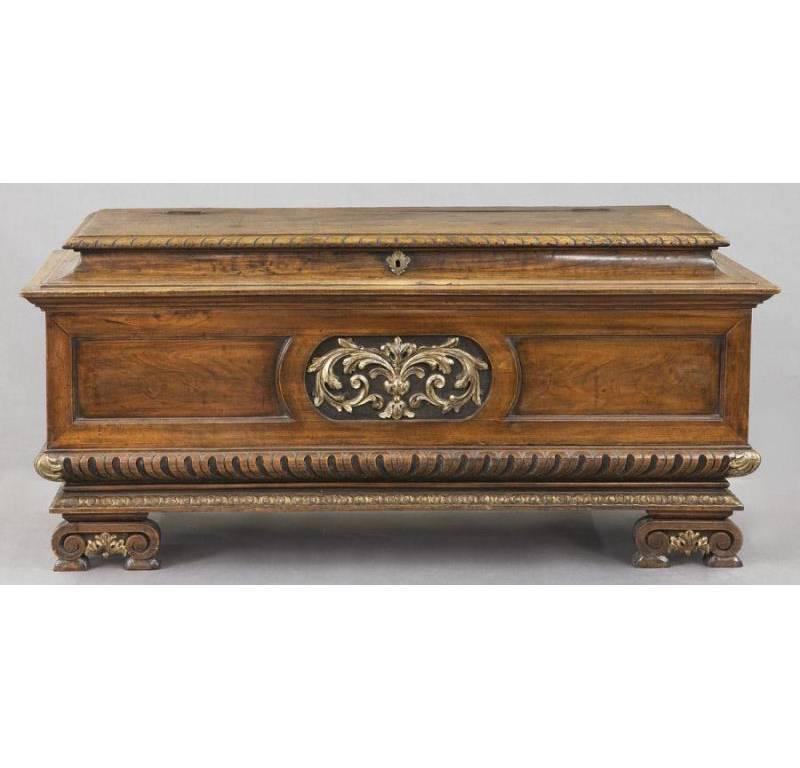 This elegant, antique fruitwood cassone was crafted in Italy, circa 1830. Standing on four scrolled feet, the base of the stately trunk is decorated with a foliate gilt medallion, and is topped with a rectangular, raised stepped tilt-top. Both top