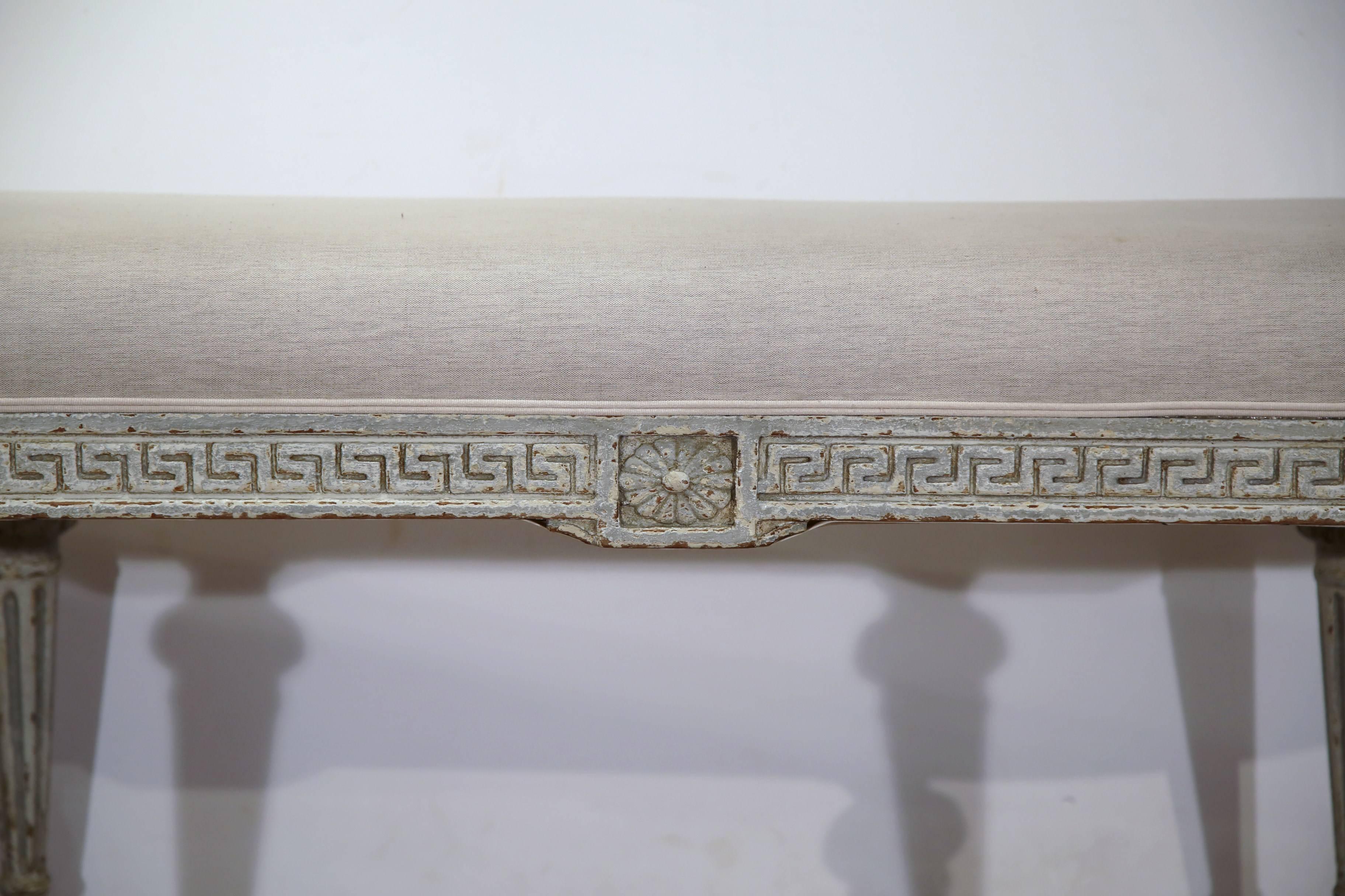 Complete your entryway or living room or bedroom with this pair of antique painted benches from France, circa 1890. These benches have a Greek design carving on the apron and six fluted legs. Both pieces have been re-upholstered with a grey toile