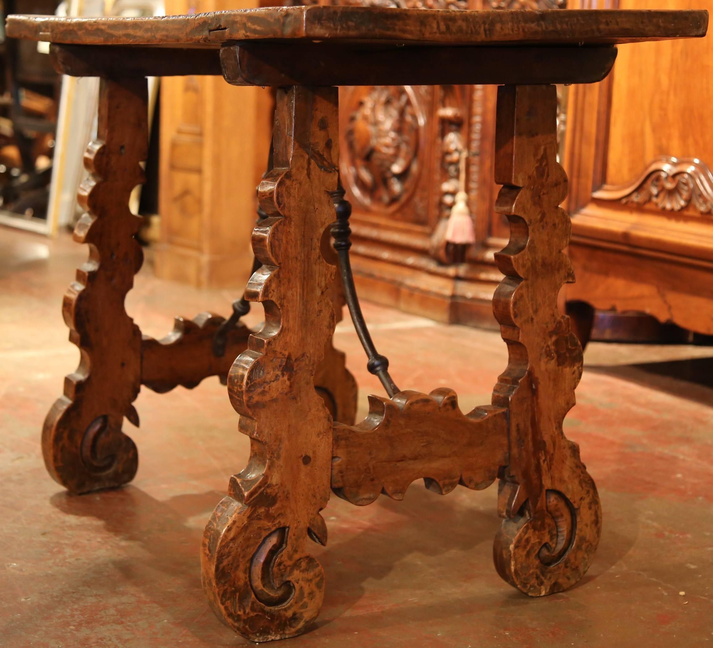This exquisite antique fruitwood table desk was carved in Spain, circa 1750. The rectangular top is made with a single piece of walnut. Underneath, there are four ornately shaped legs and an original wrought iron stretcher. The rustic, Spanish side