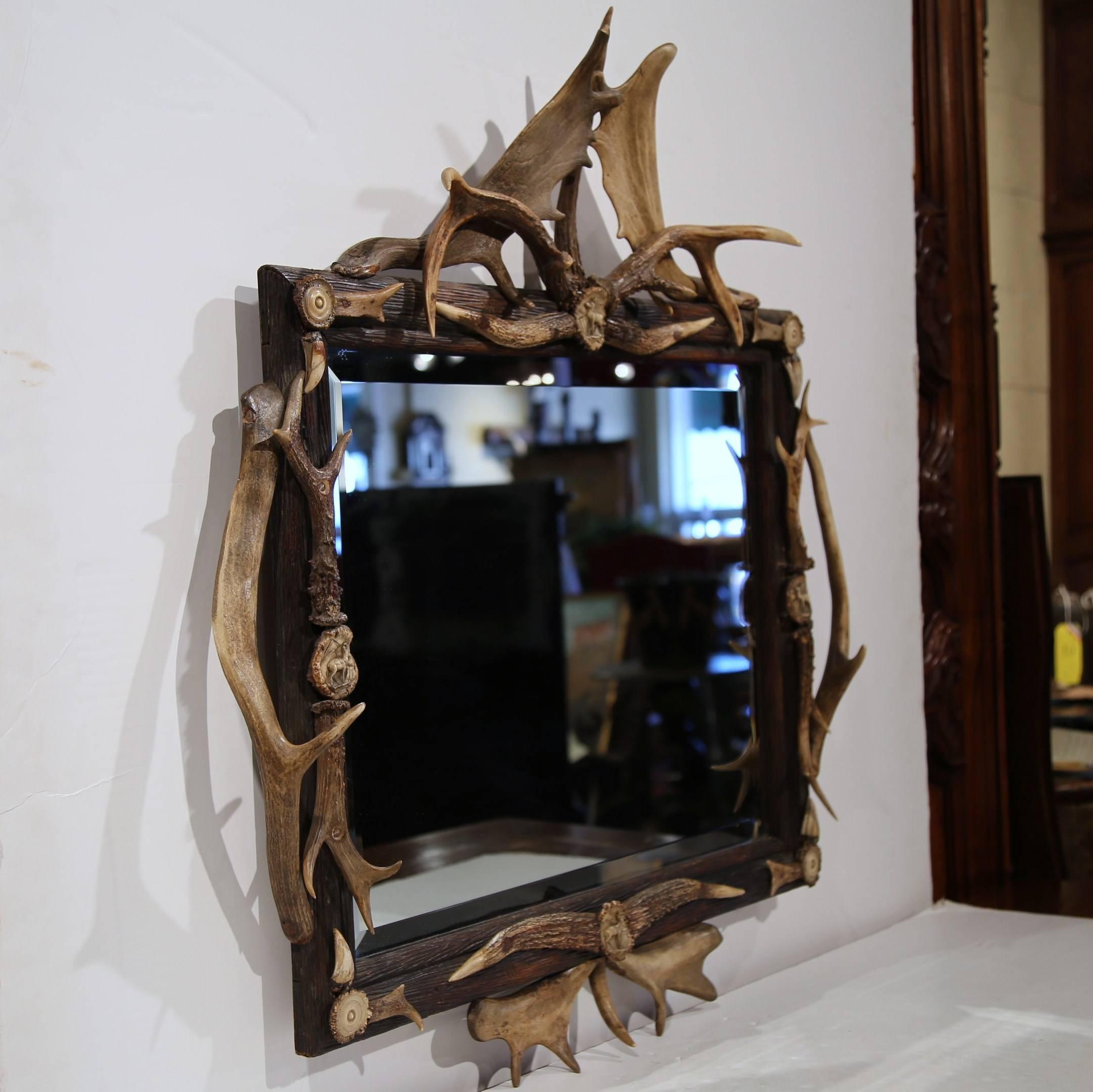 Fabulous antique mirror from Switzerland, circa 1860 with elk, chamois and deer antlers around the frame. Each center medallion features a carved deer with additional round medallions in every corner. Original beveled glass mirror.