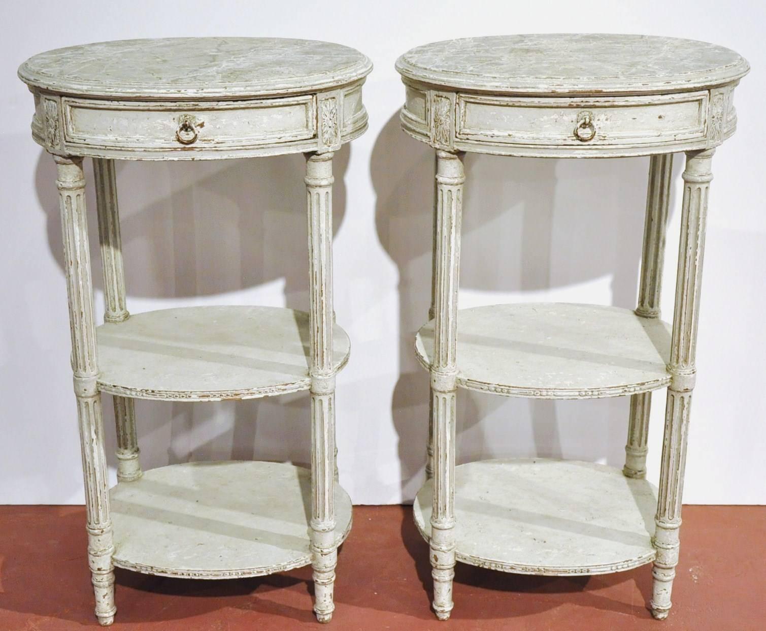 Elegant pair of antique side tables from France, circa 1880. Delicate fluted legs with double tier shelves and drawers. Faux marble on oval shape top. A true one of a kind! Could be used as bedside tables or nightstands.