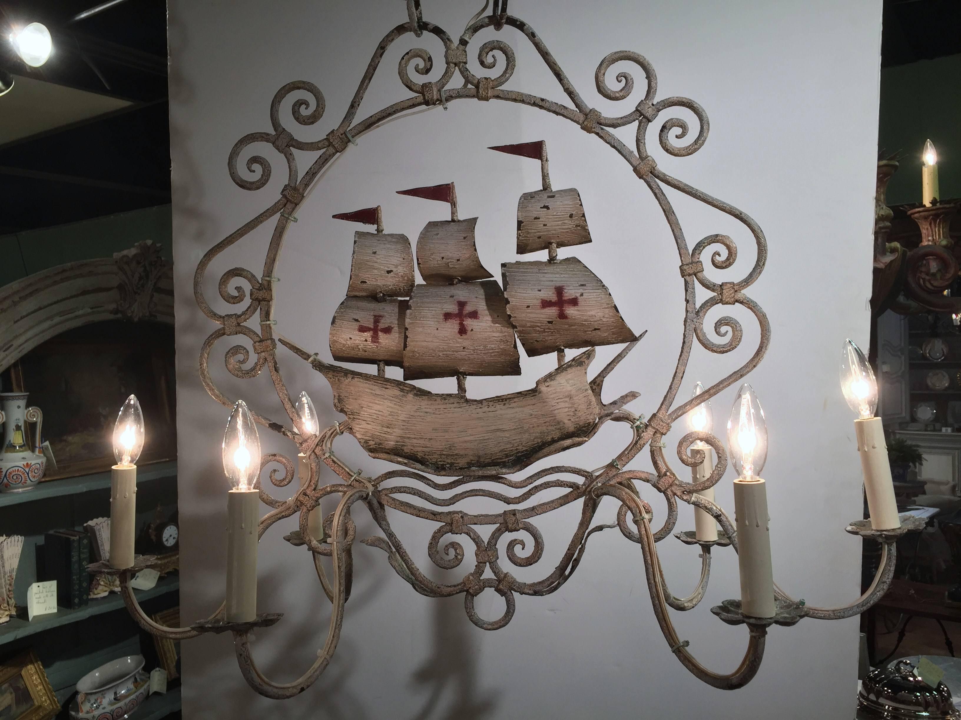 This interesting vintage chandelier was crafted in Normandy, France, circa 1960. Oblong in shape, the fixture has six newly wired lights and is hand painted in a beige, off-white palette. In the middle of the frame is a Classic ship with sails and