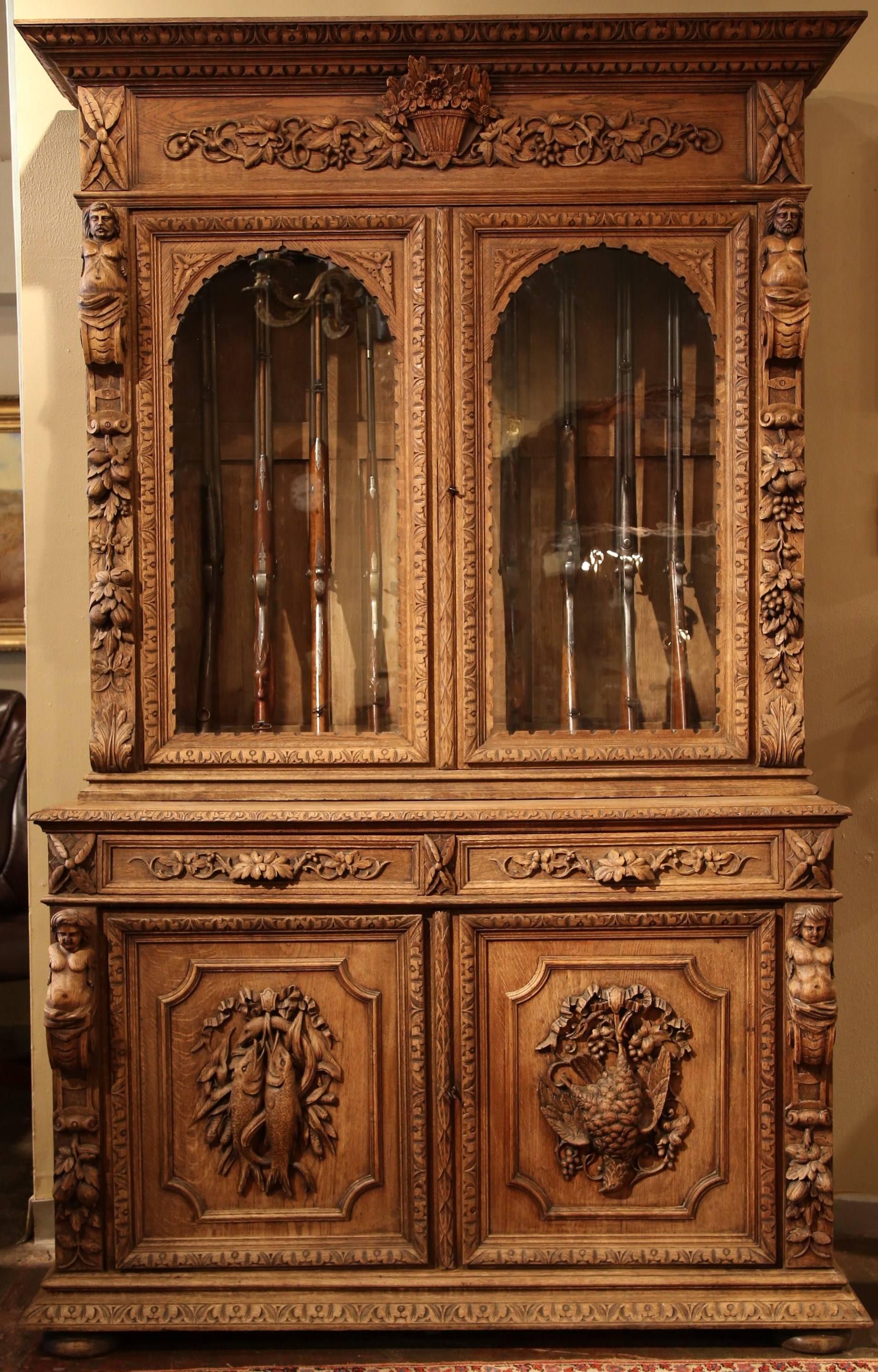 Fabulous antique heavily carved buffet deux corps from France, circa 1870. This 9-gun cabinet has been stripped and refinished in a lighter color. Representing 