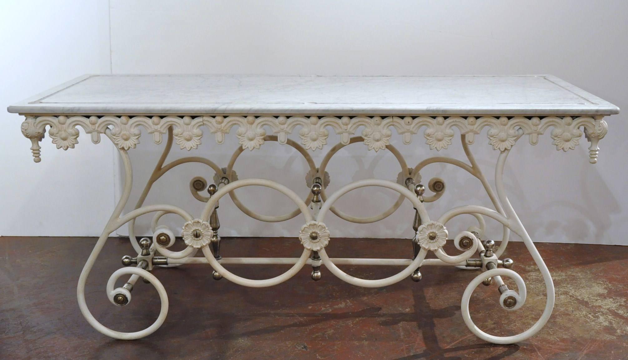 Elegant painted butcher table from France with white marble top, ornate cast freeze, graceful scrolled steel legs with brass fitting and finials.
 The French 