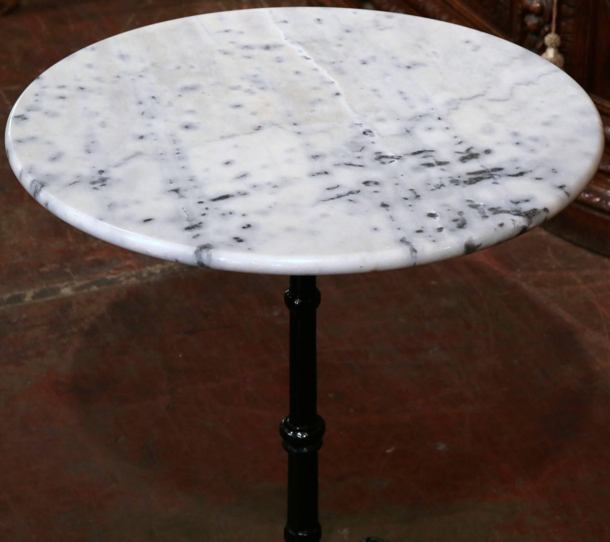 Turn of the century round bistro table from France, circa 1920. Single ornate pedestal with black paint and white/grey marble top. Excellent condition.
