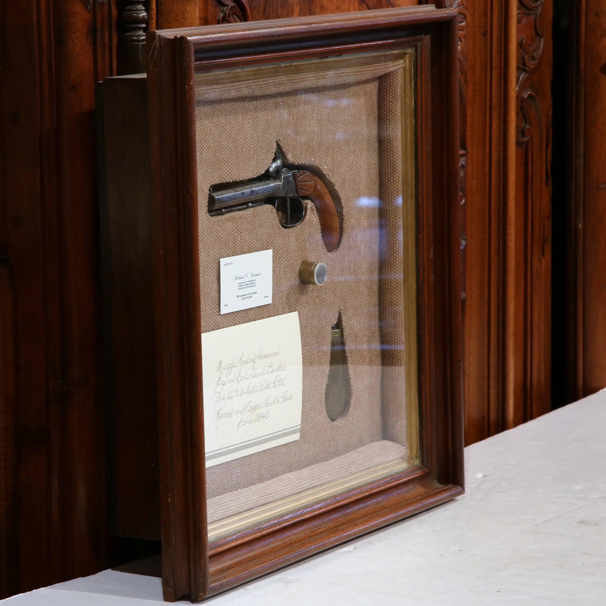 Place this framed vitrine with glass door in an office or game room. Crafted in England, circa 1840, the decorative antique piece features a one of a kind British antique muzzle loading percussion gap and ball double barreled side by side pistol,