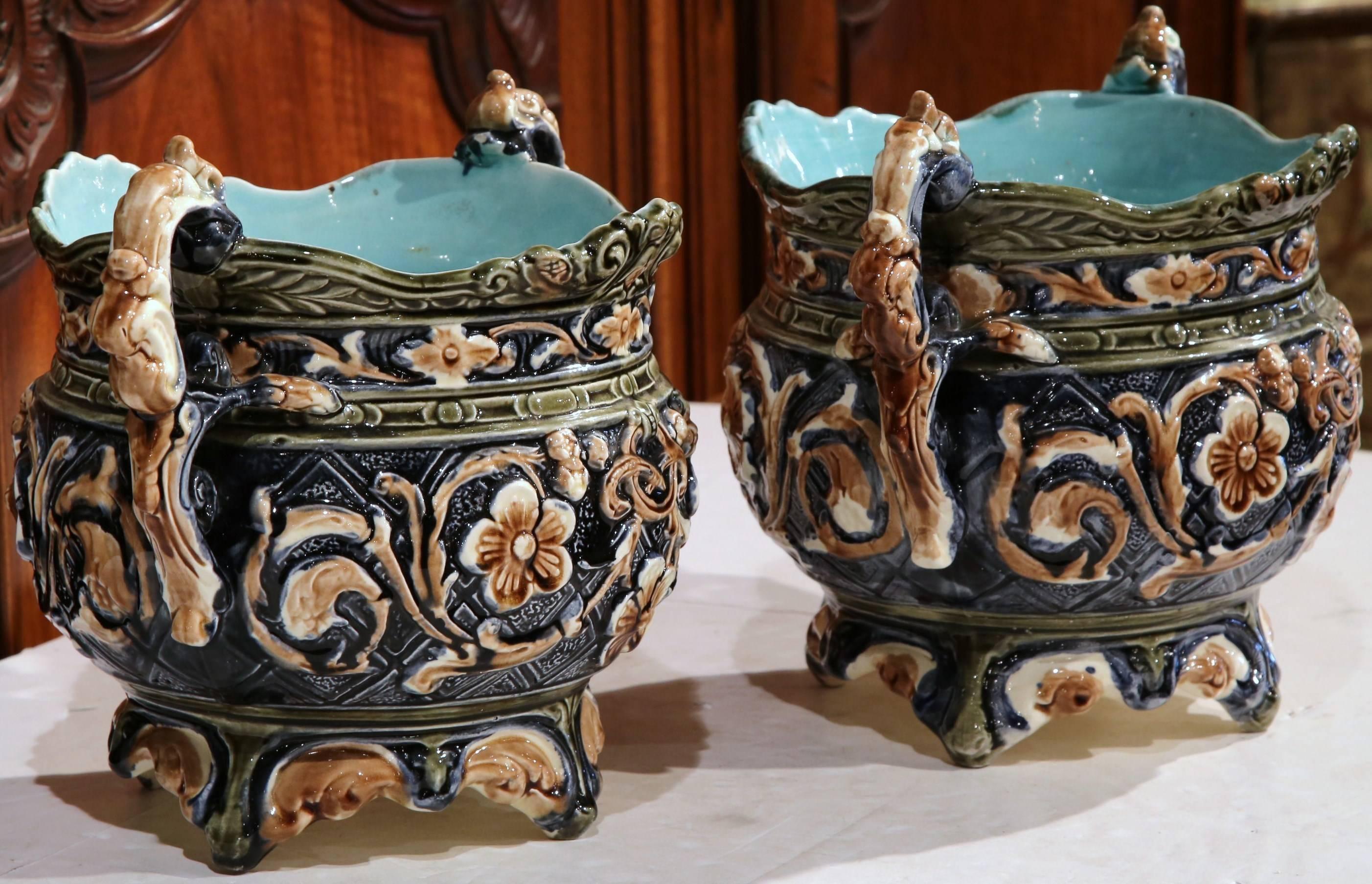 Decorate a mantel (fireplace) or buffet with this colorful pair of antique Majolica vases. The two, ornate, sculptural pots sit on small feet and feature decorative handles on either side; sculpted in France, circa 1890, the ceramic vases have a