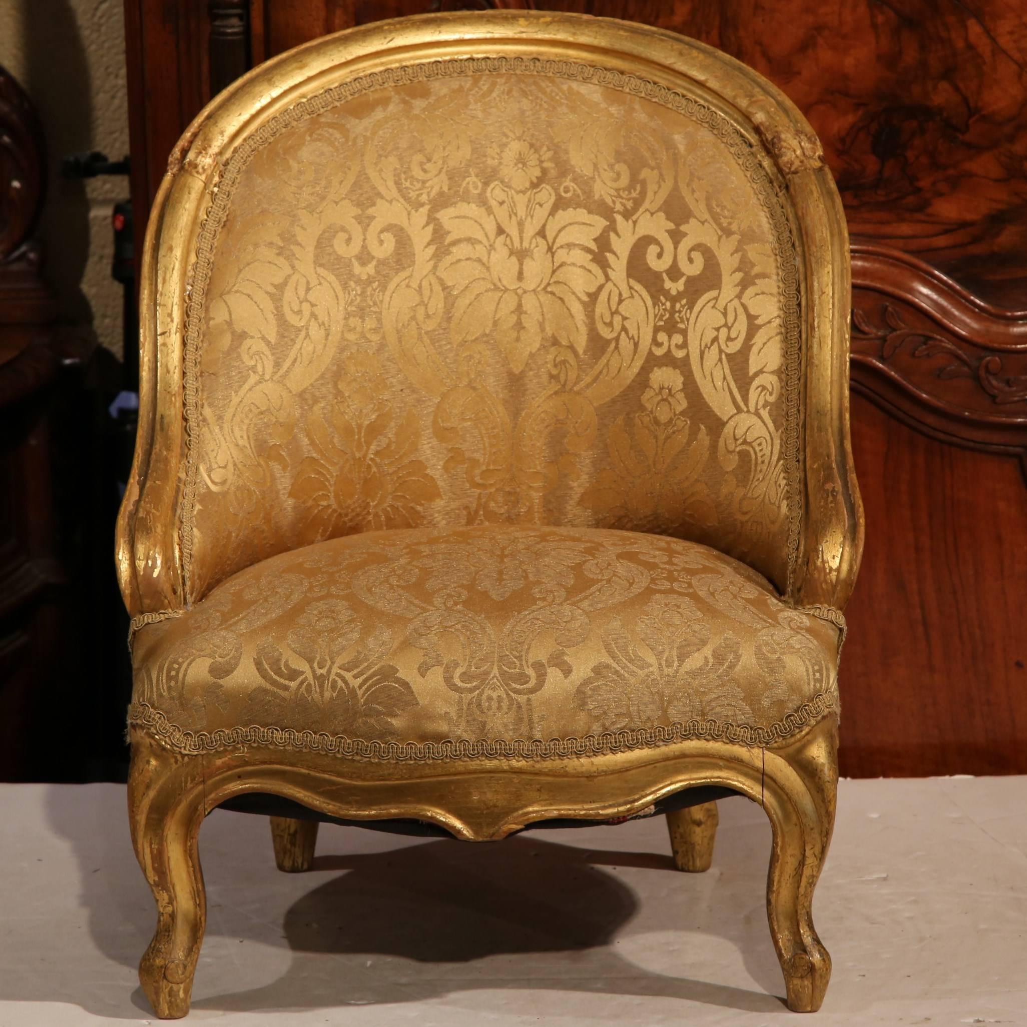 This elegant, antique children's armchair was crafted in France, circa 1850. The rounded, high back chair has a frame embellished with its original gold leaf finish. The Louis Philippe chair has been reupholstered with a Fortuny-like fabric that has
