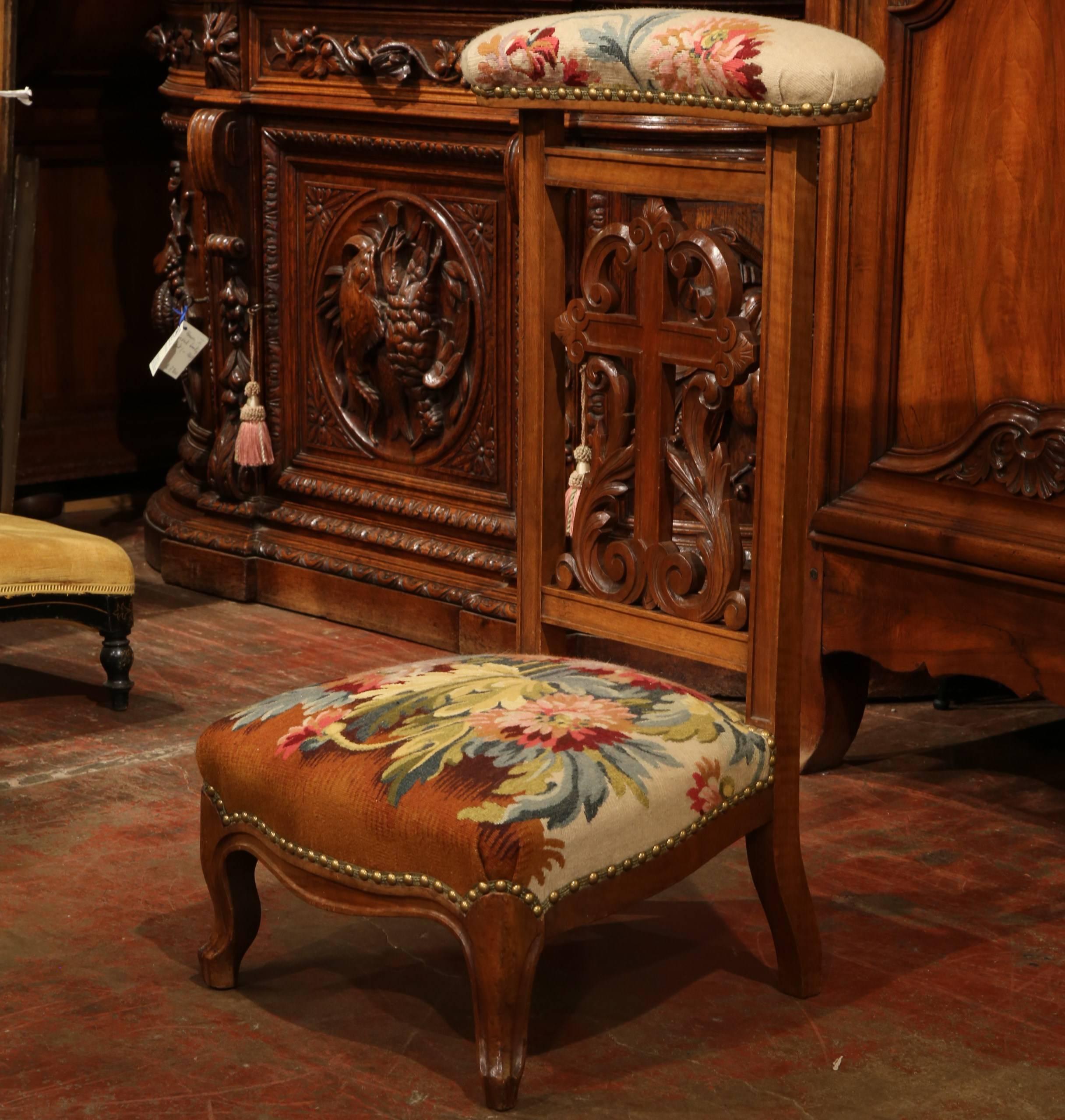A classic antique prayer kneeling chair or prie-dieu from France, circa 1870. The kneeling chair features a carved cross and scrolls on the back and curved feet on the front. The armrest and the knee rest seat have been redone and reupholstered with