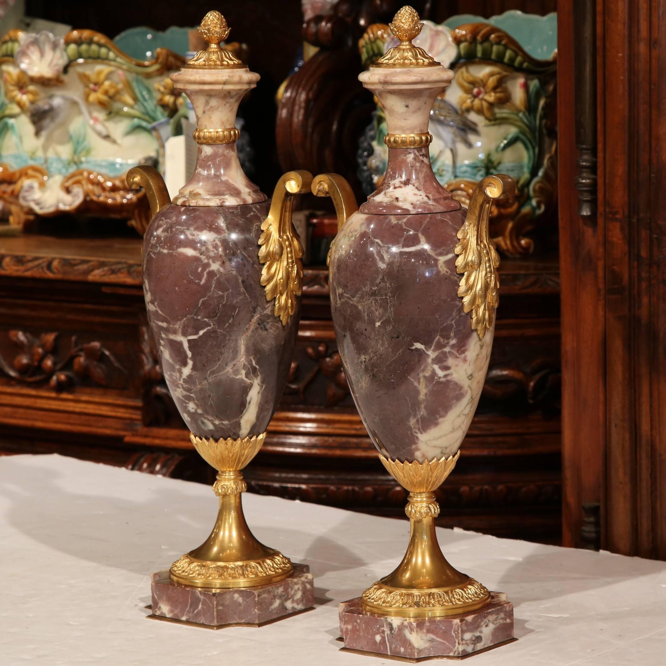 Make a statement on your mantel with this elegant pair of antique marble cassolettes. Crafted in France, circa 1860, the decorative urns have bronze ornaments and mounts from top to bottom, including intricate handles. The base of the urns have a