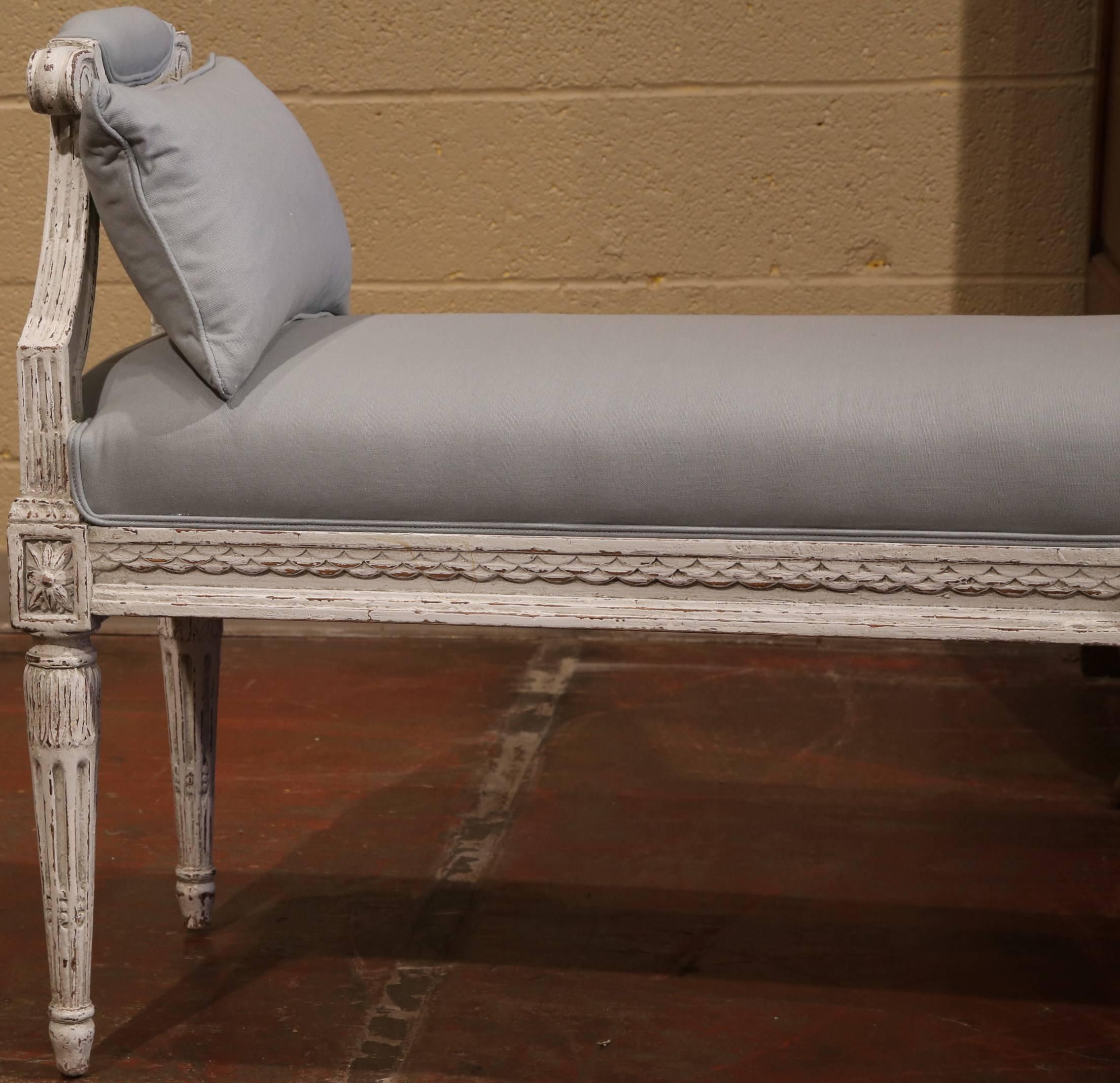 This elegant antique six-legged bench from France was crafted, circa 1890. The beautiful piece has a carved apron embellished with rosettes, and tapering, fluted legs. Complete with a patinated, painted finish and grey upholstered cushions, the long