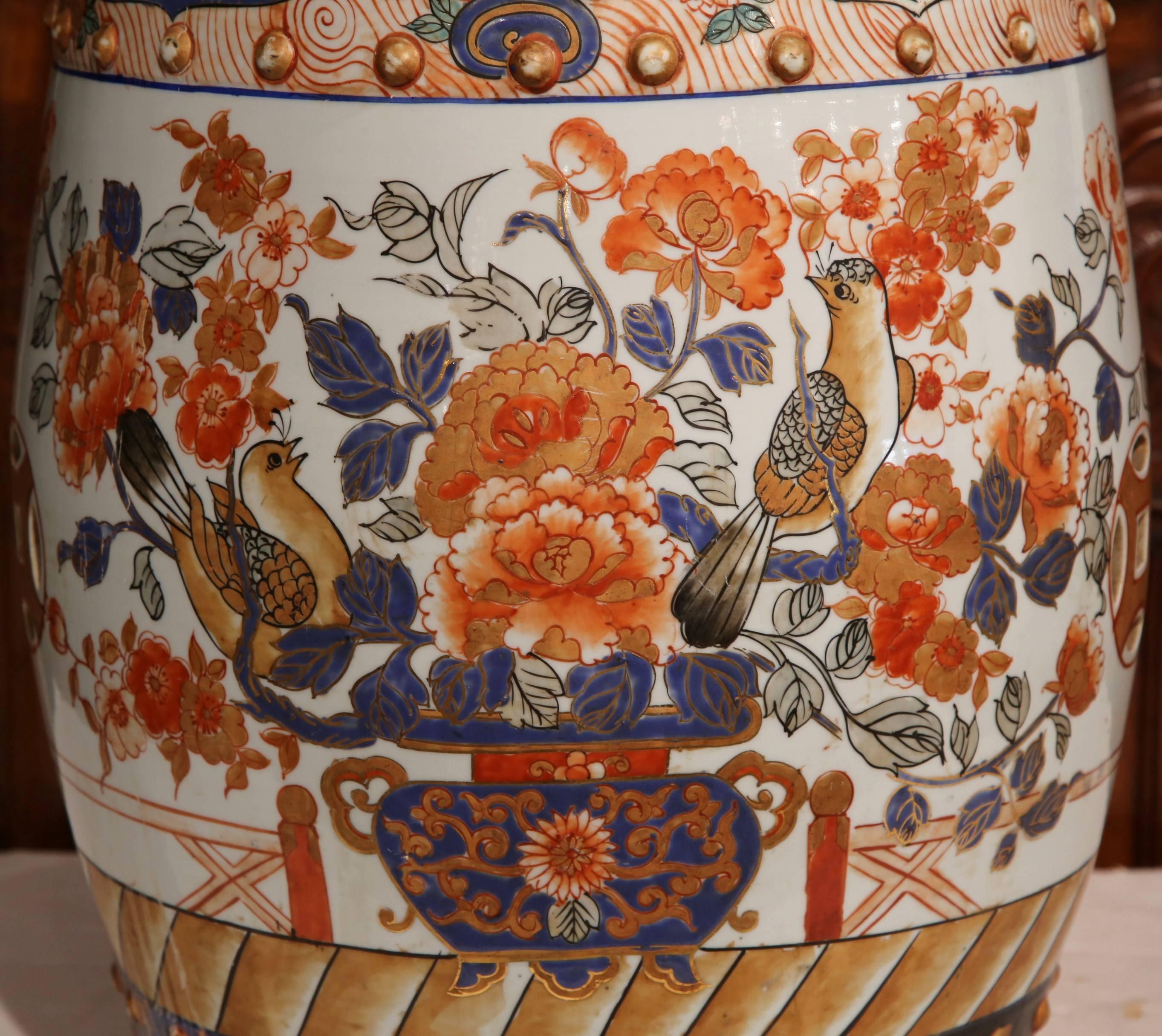 This antique porcelain garden seat was found in France, but created in Japan, circa 1870. The ornate ceramic piece features hand-painted scenes of flowers and birds with unmistakable oriental flair. The stool has a varied palette of navy blue,