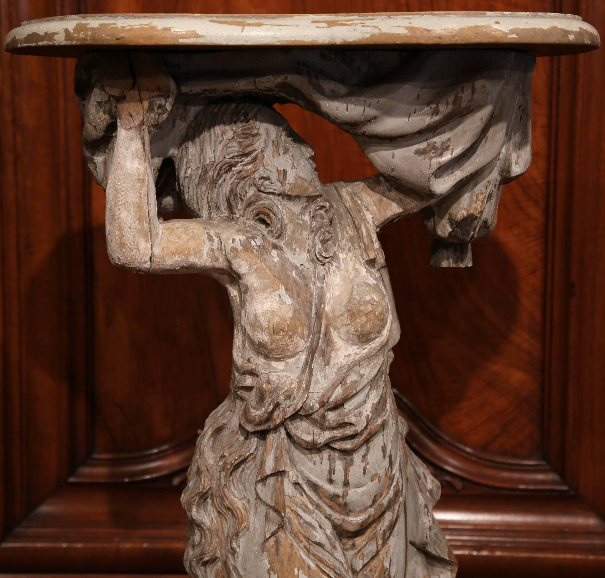This exquisite, antique figure was carved in France, circa 1750. The sculpture features a neoclassical Grecian woman wearing Classic robes and holding a tabletop, an element that was added later to convert the sculpture into a pedestal table. The