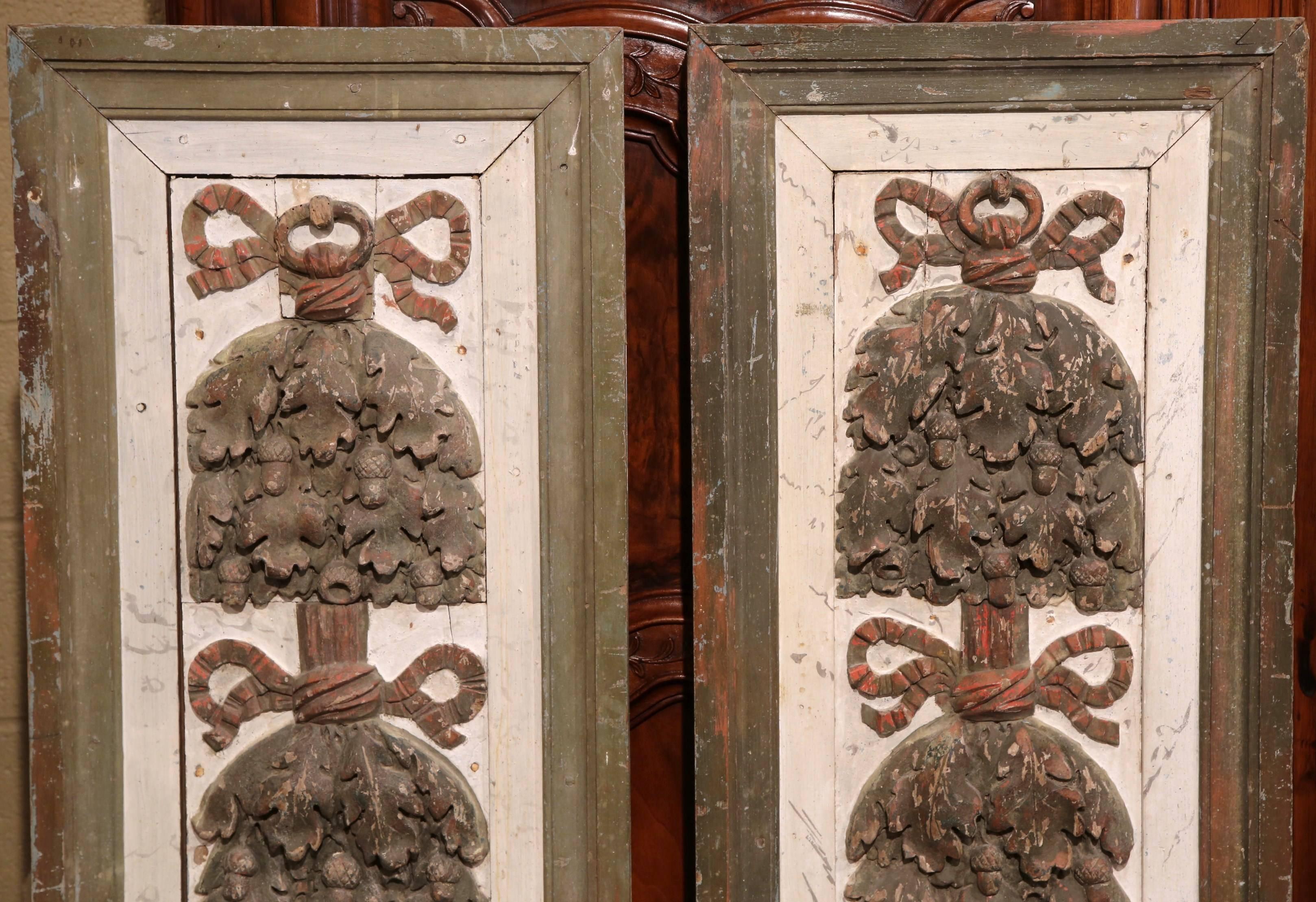This unique pair of antique panels were carved during the Louis XVI period in Versailles, France in 1760. The panels feature four hand-carved floral motifs with leaves and acorns. Underneath each arrangement, you'll find a signature Louis XVI bow on