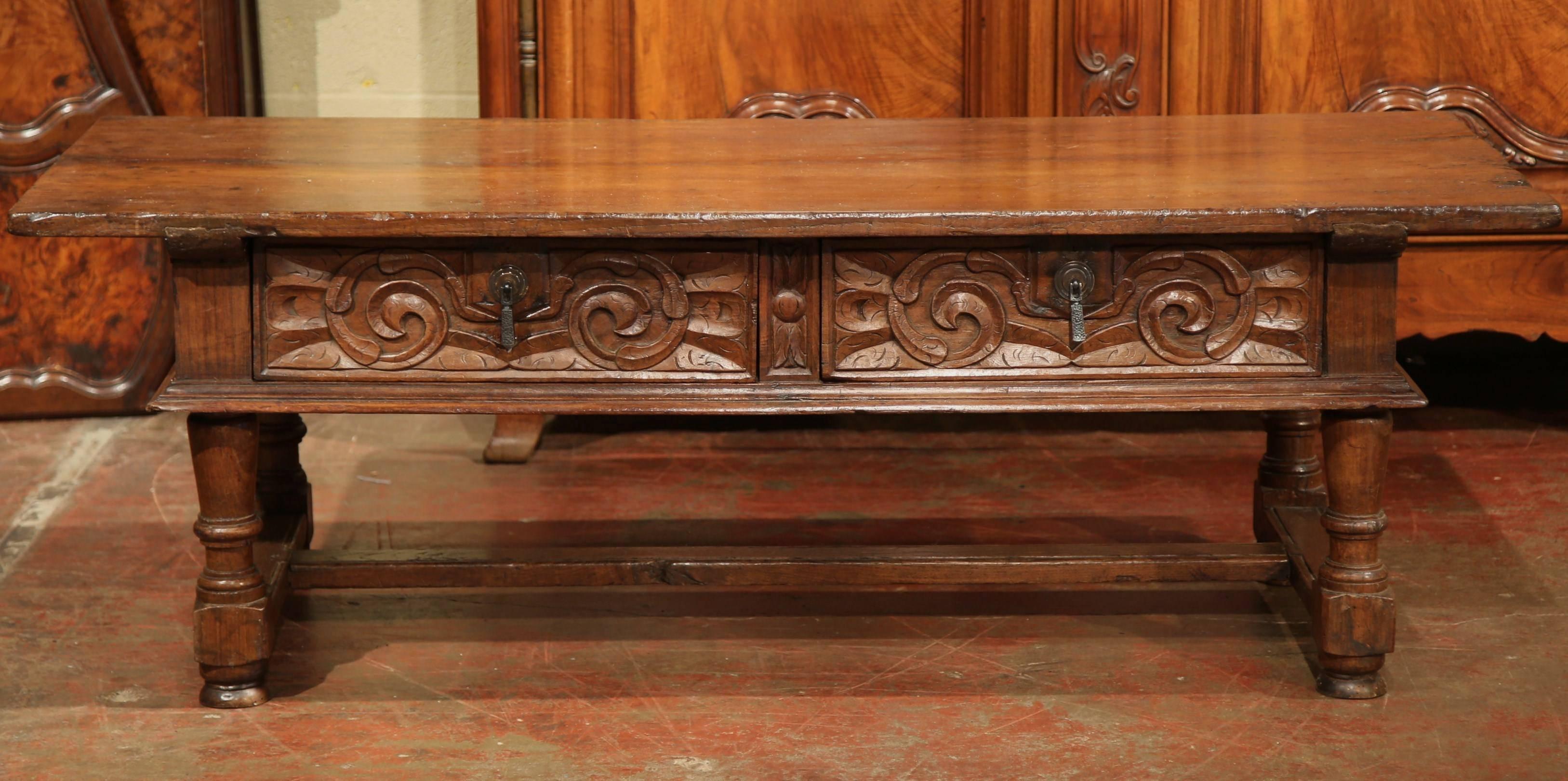 This elegant, chestnut antique coffee table was carved in the Southern mountains of France, circa 1820. Intricately carved on all four sides, this cocktail table features four turned legs, a bottom stretcher and two drawers across the front with