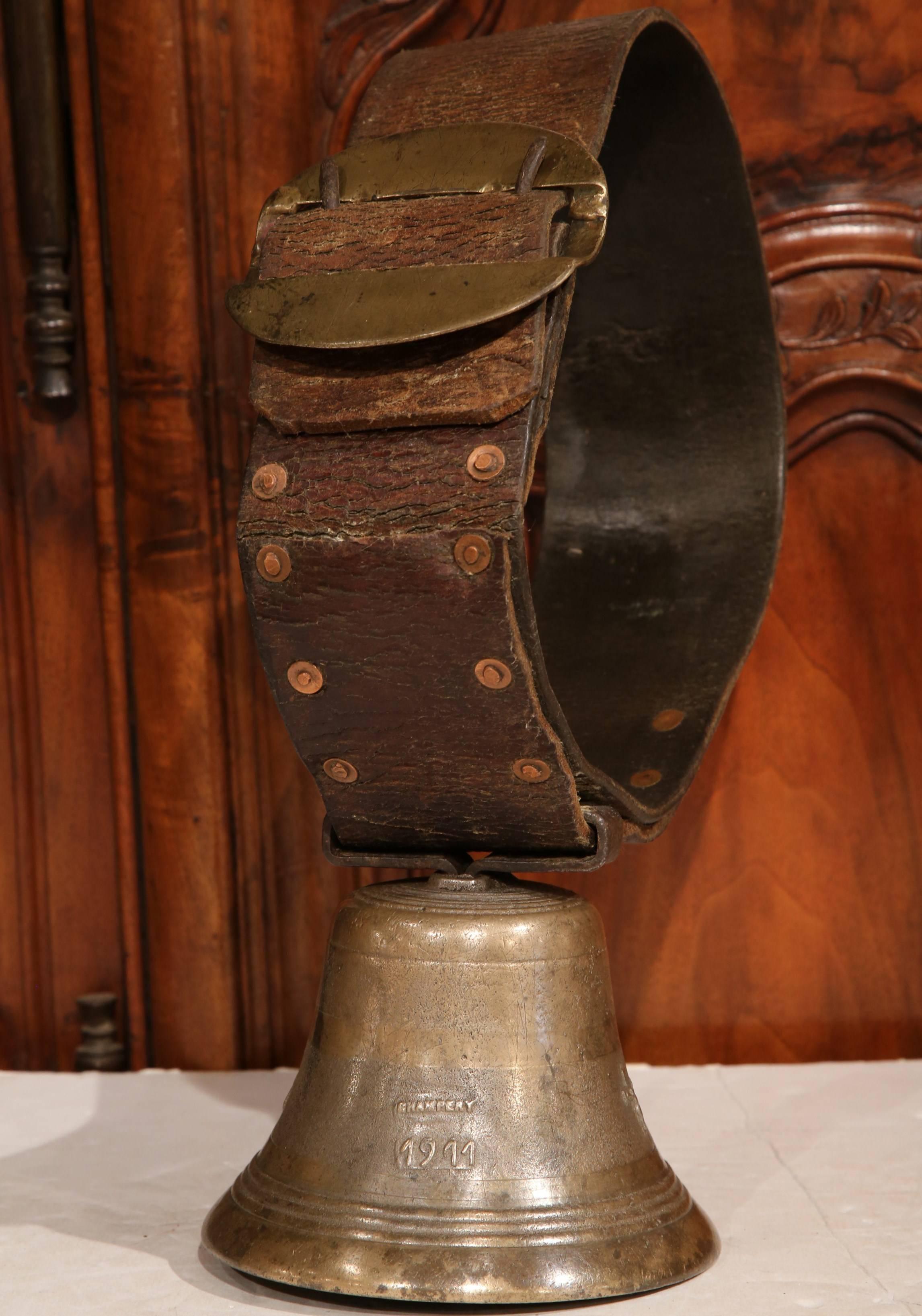 This antique bronze bell was crafted in the village of Champery, Switzerland in 1911. The bell features its original leather collar, and includes a variety of motifs from Christ on a cross to a cow with the date and foundry place. These kinds of