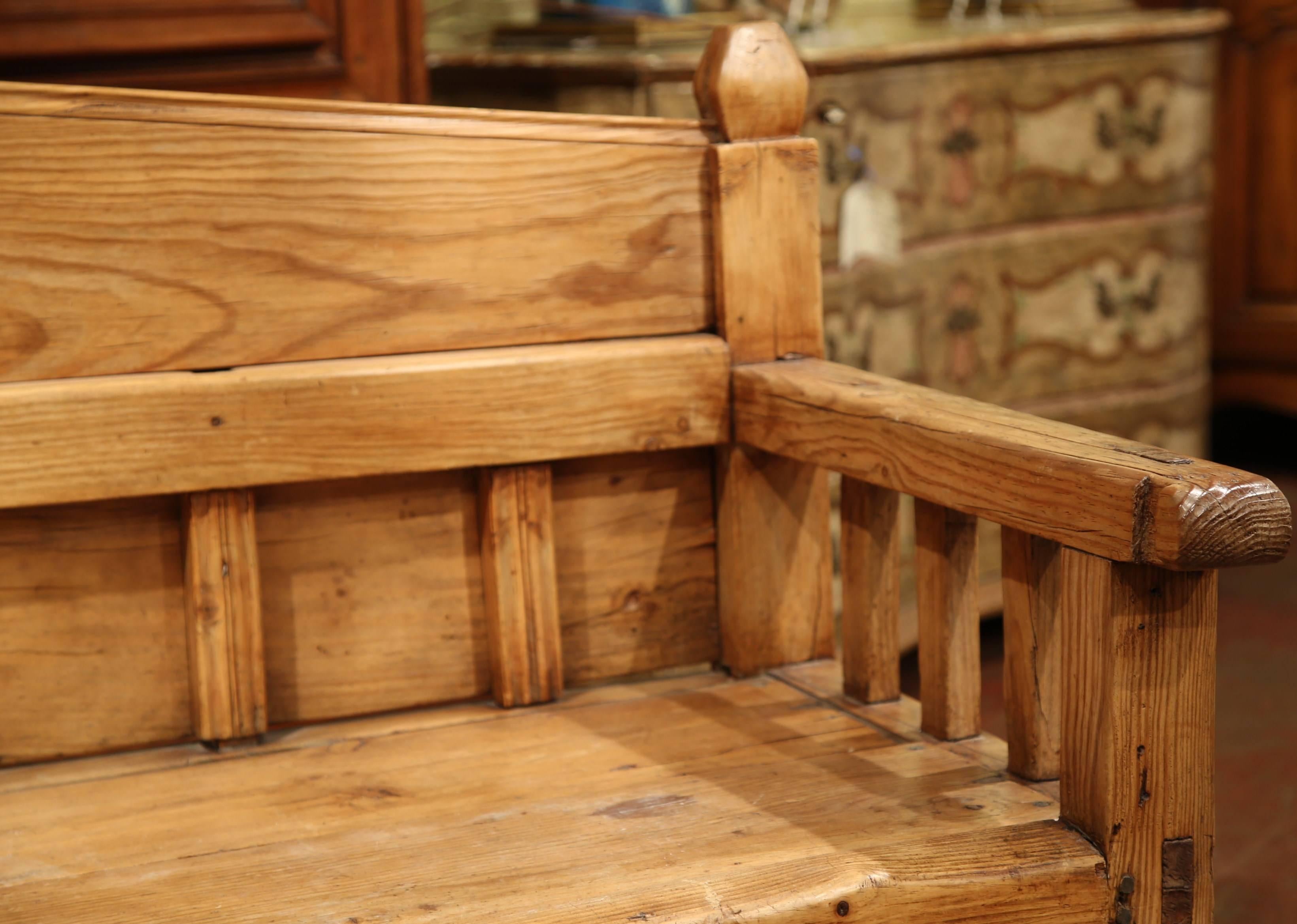 This simple, rustic four-leg pine bench derives from the south of France, circa 1870. The wooden casual bench stands on four straight legs and features carved decors including vertical posts on the armrests and back, and finials on the arched back.