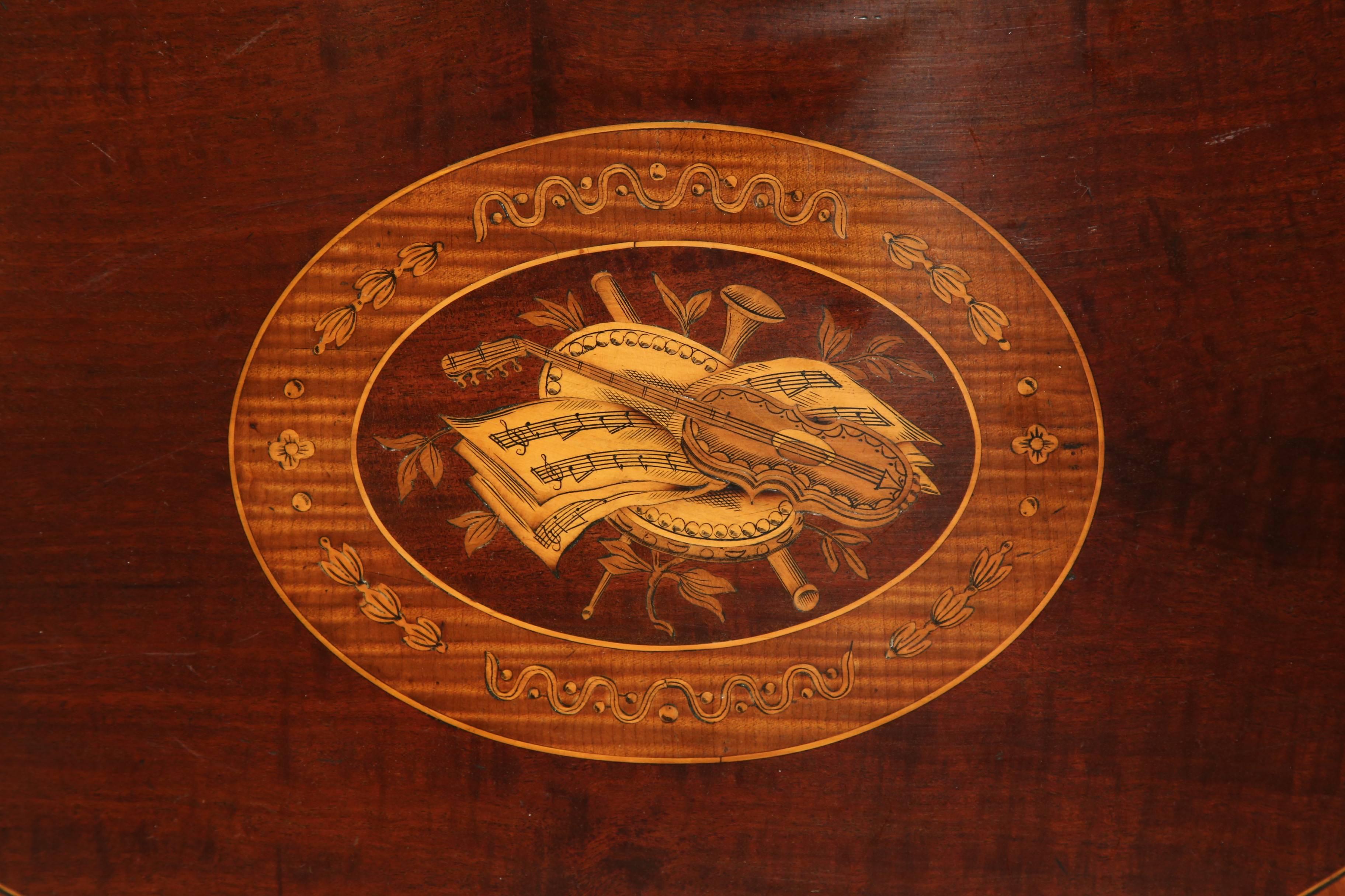 Embellish a coffee table or countertop with this beautiful, early 20th century mahogany tray from England, circa 1920. The serving tray features a central design with inlaid musical instruments and sheet note music. On the periphery is an additional