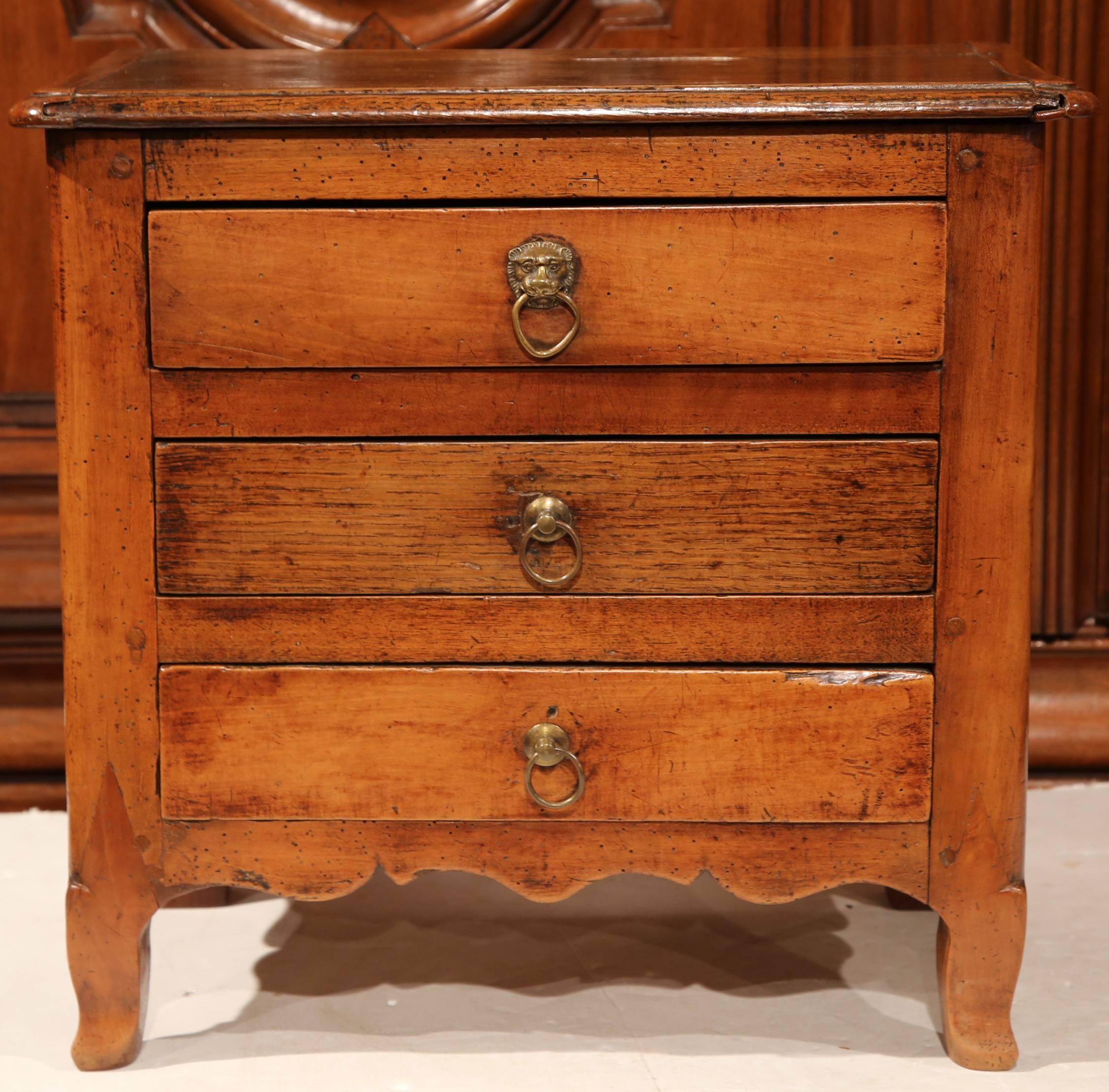 Protect jewelry and other small treasures in this antique fruitwood miniature chest of drawers from France, circa 1820. The small commode has three drawers with brass handles, a scalloped apron with scrolled feet and a rich walnut patina throughout.
