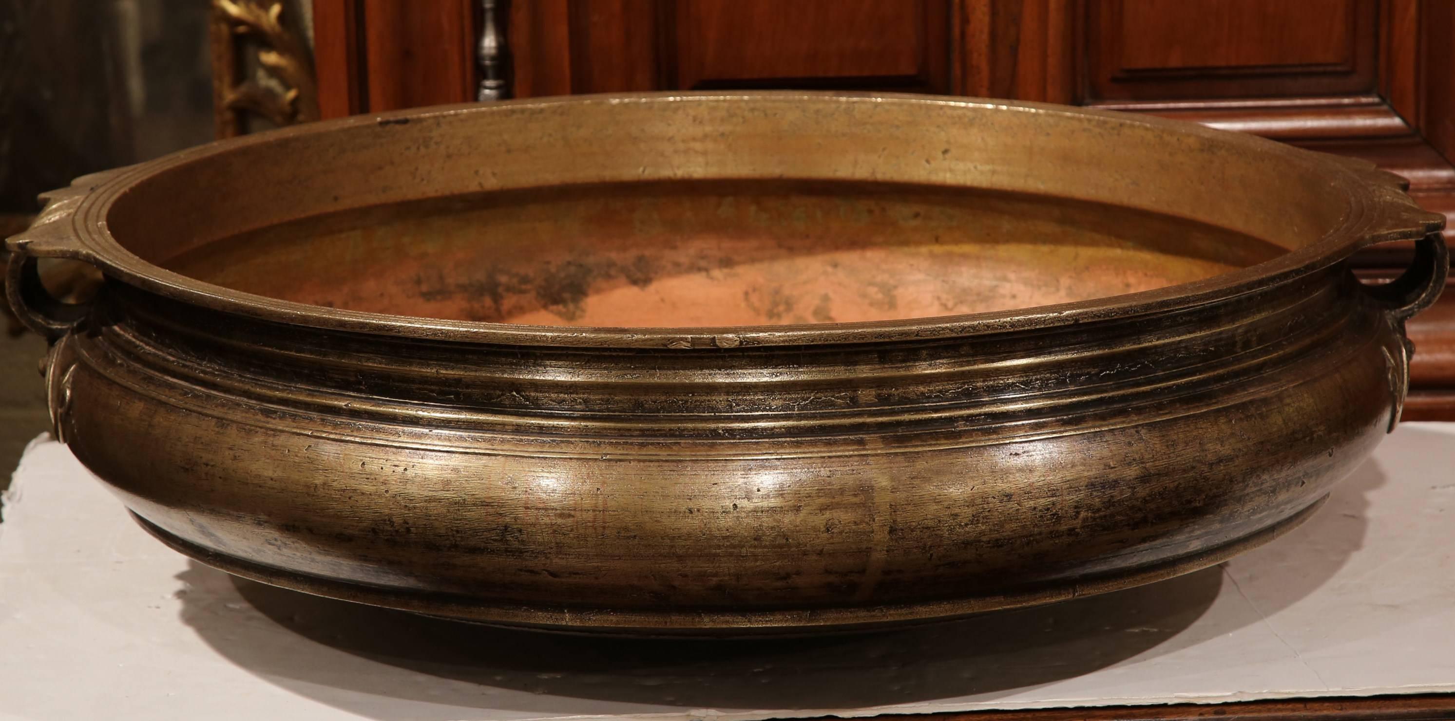 Decorate a table or countertop with this elegant bronze cooking dish. Crafted in Southern India, circa 1860, the antique Urli has a neoclassical shape with wide mouth, short height and handles on both sides and Fleurs de Lys detail. This dish was a